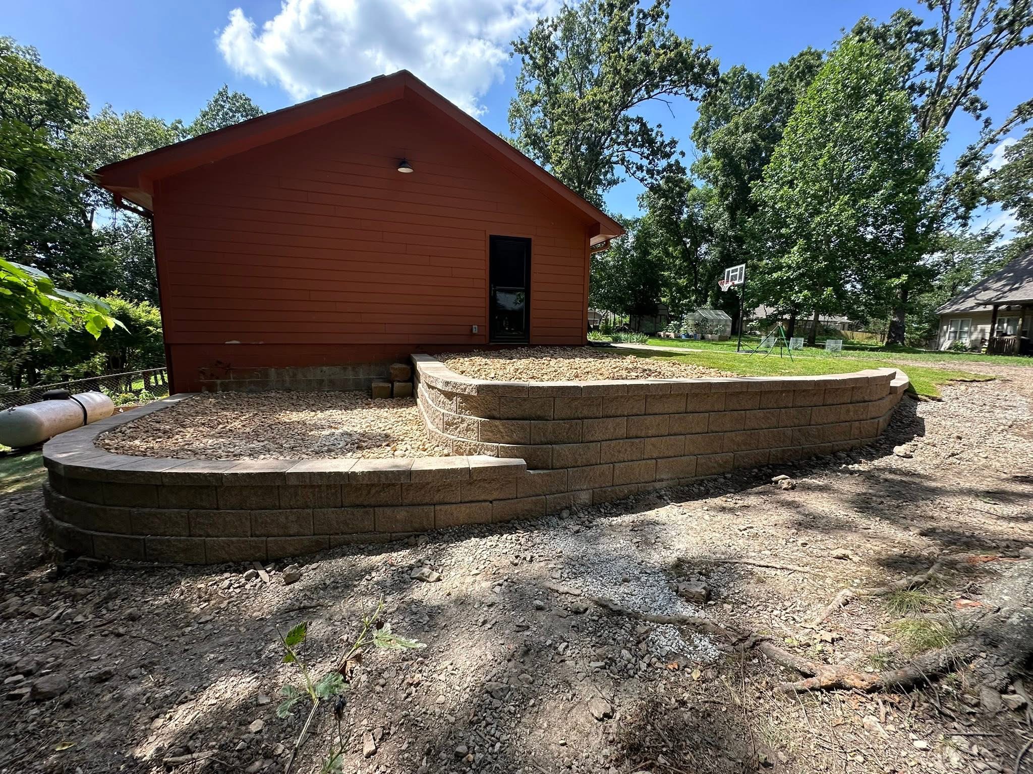 Curved segmental block retaining wall with gravel backfill on a residential property, built by Stukes Construction