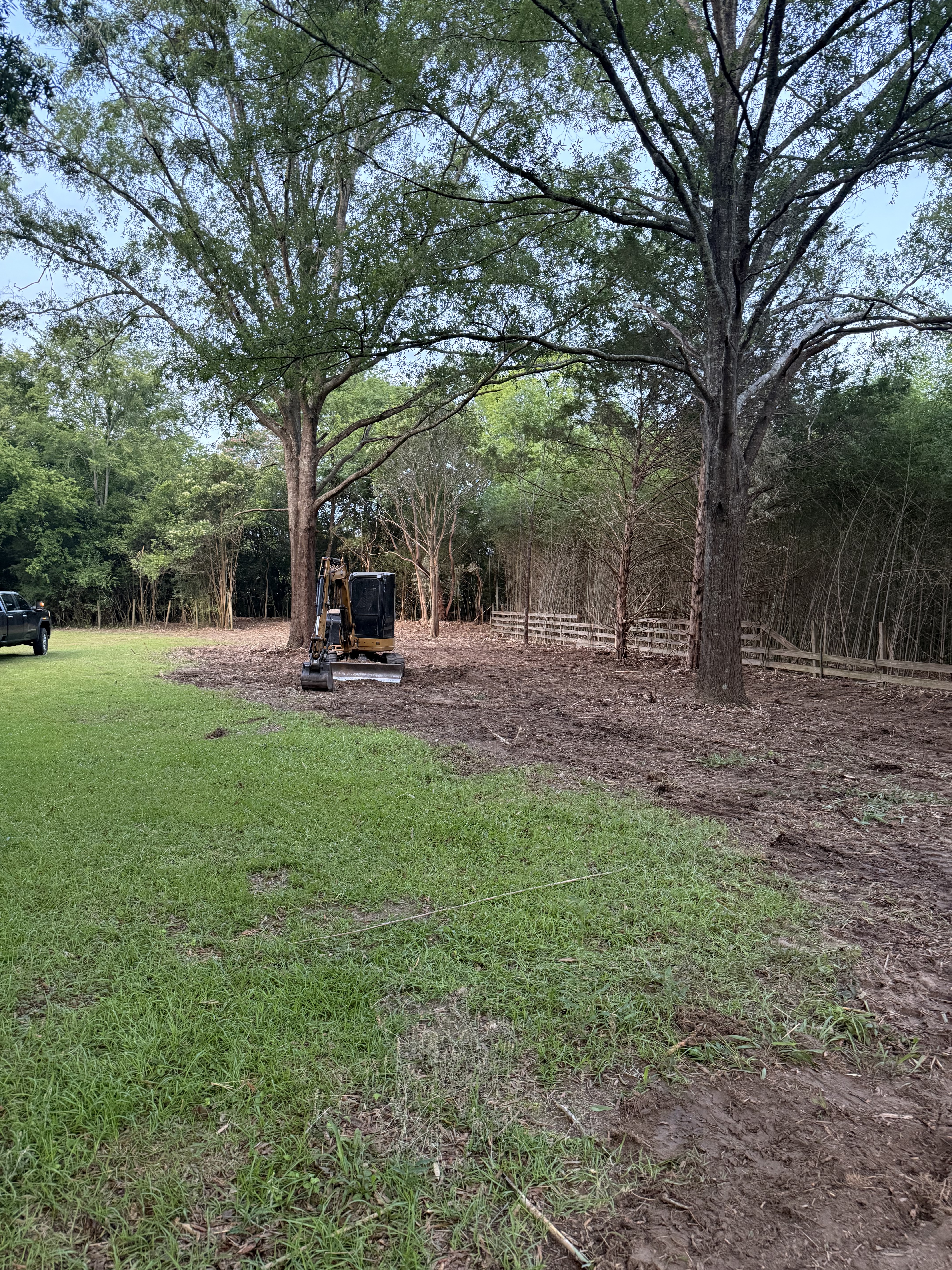 Mini excavator clearing underbrush and vegetation from a residential backyard property, by Stukes Construction