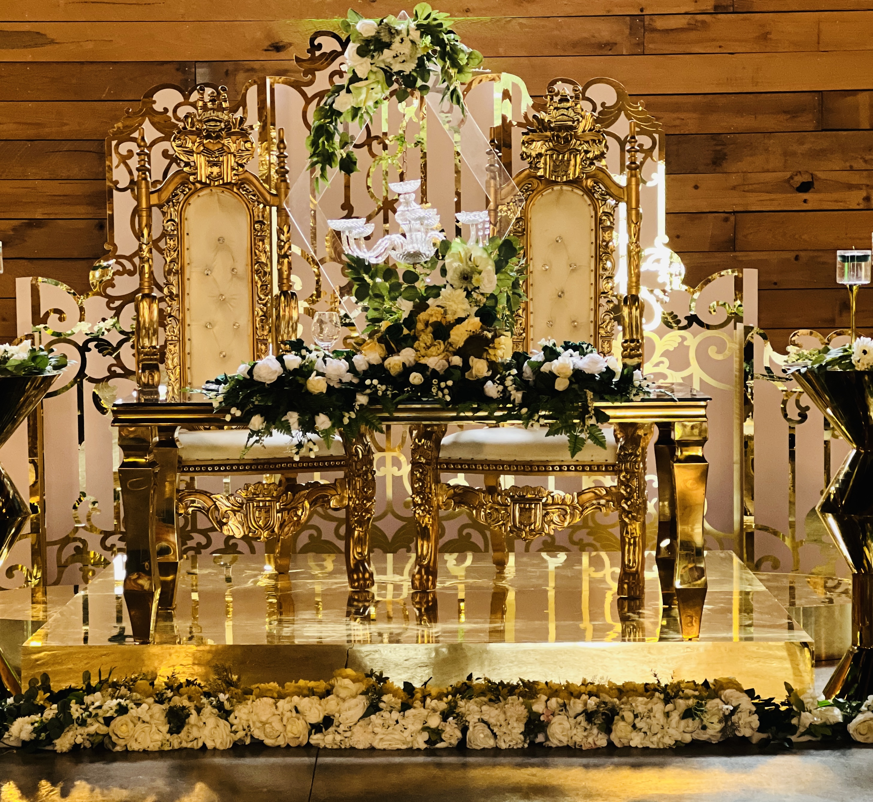 Gold throne sweetheart table with ornate backdrop and floral arrangements