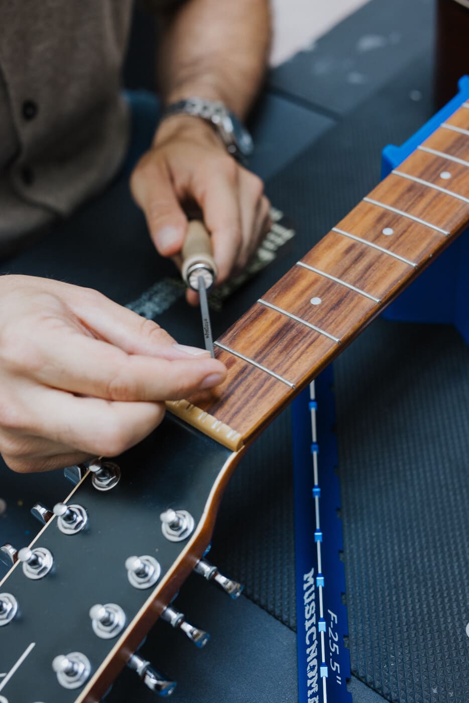 Tyler's hands working on guitar frets with a precision screwdriver - guitar repair and maintenance