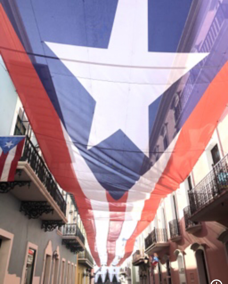 Giant Puerto Rican flag stretched as a canopy over a street in Old San Juan β red, white, blue, and the lone star