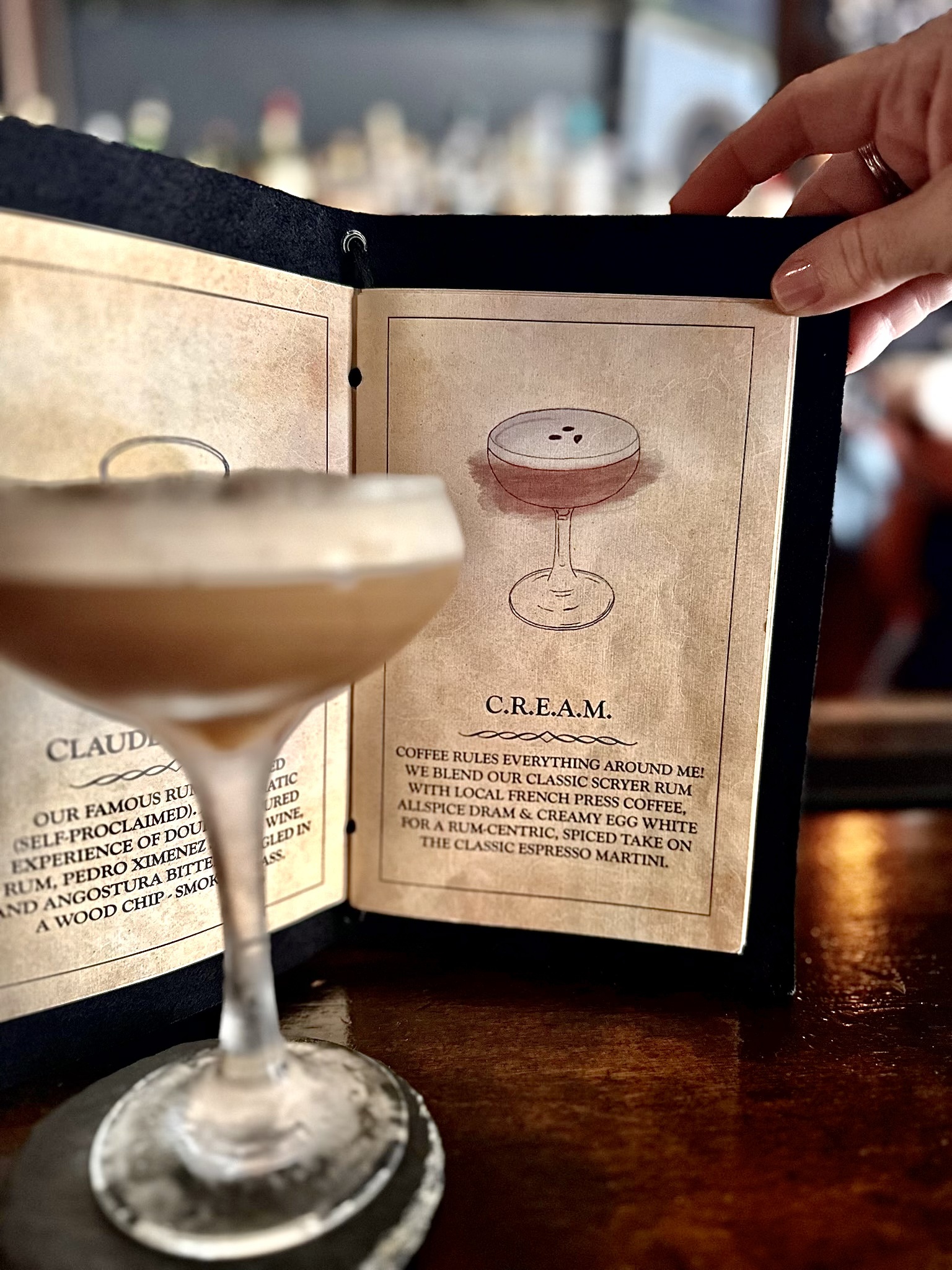 C.R.E.A.M. cocktail at Scryer Rum Barrelhouse \u2014 rum-centric espresso martini in a coupe glass with the C.R.E.A.M. menu page open showing Coffee Rules Everything Around Me, Scryer Rum blended with local French press coffee, allspice dram and creamy egg white