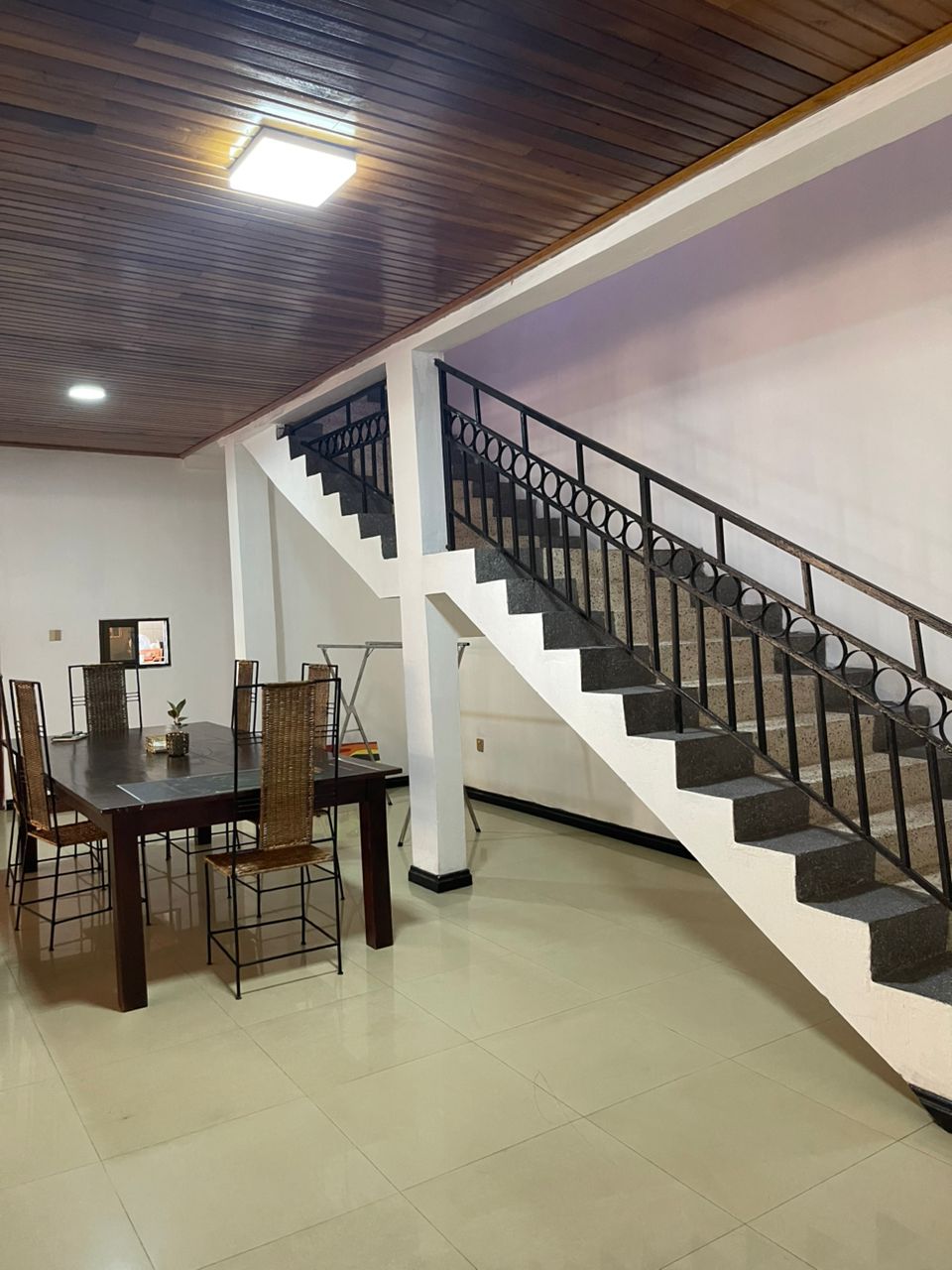 Nteasee House dining area with wooden ceiling, dining table, and staircase