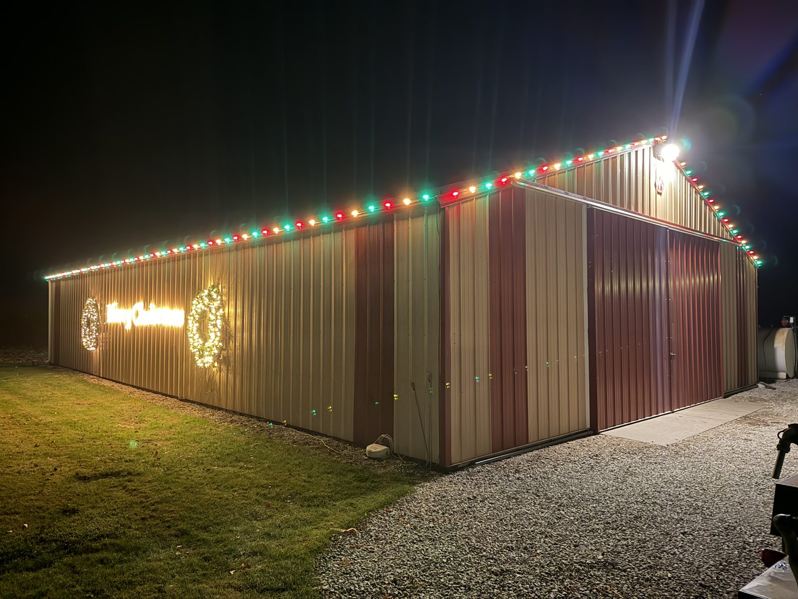 Outbuilding with colored roofline lights and lit wreath — Christmas lighting by Lincoln Creek Landscape & Design