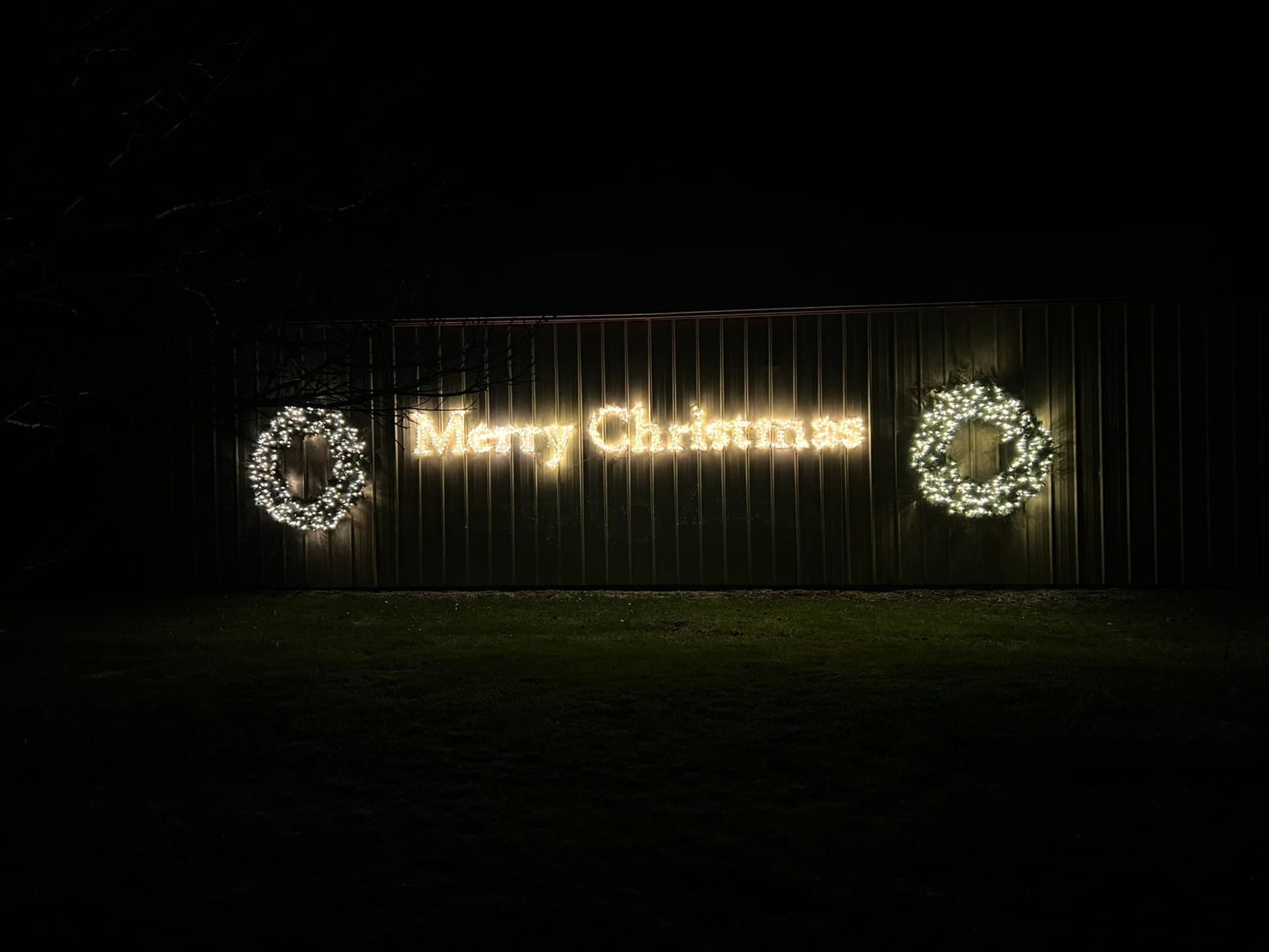 Lit Merry Christmas sign and wreaths on a building — custom holiday lighting in central Nebraska
