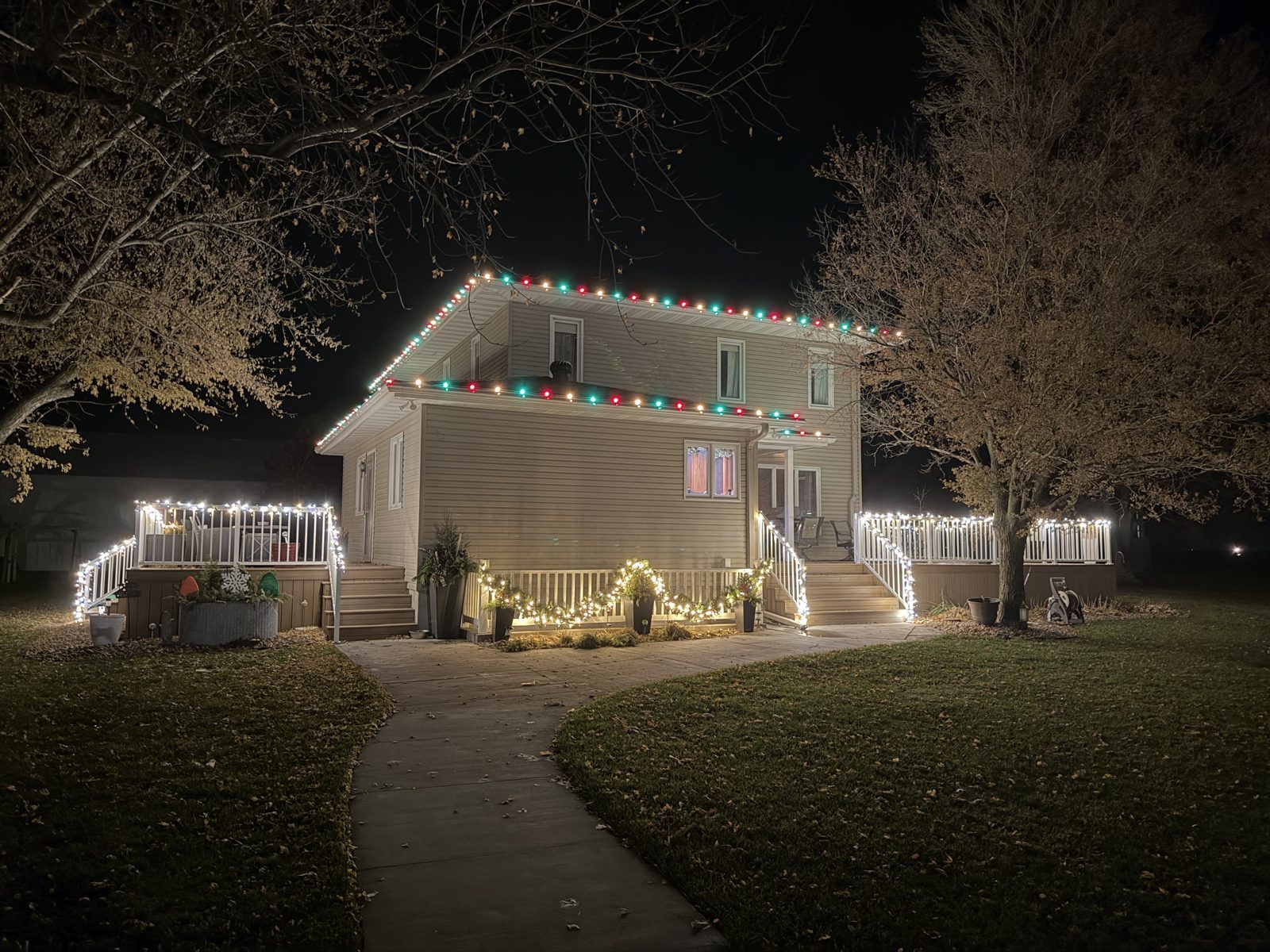 Red, green and white Christmas lights on a two-story home and porch railing — Nebraska holiday lighting installation