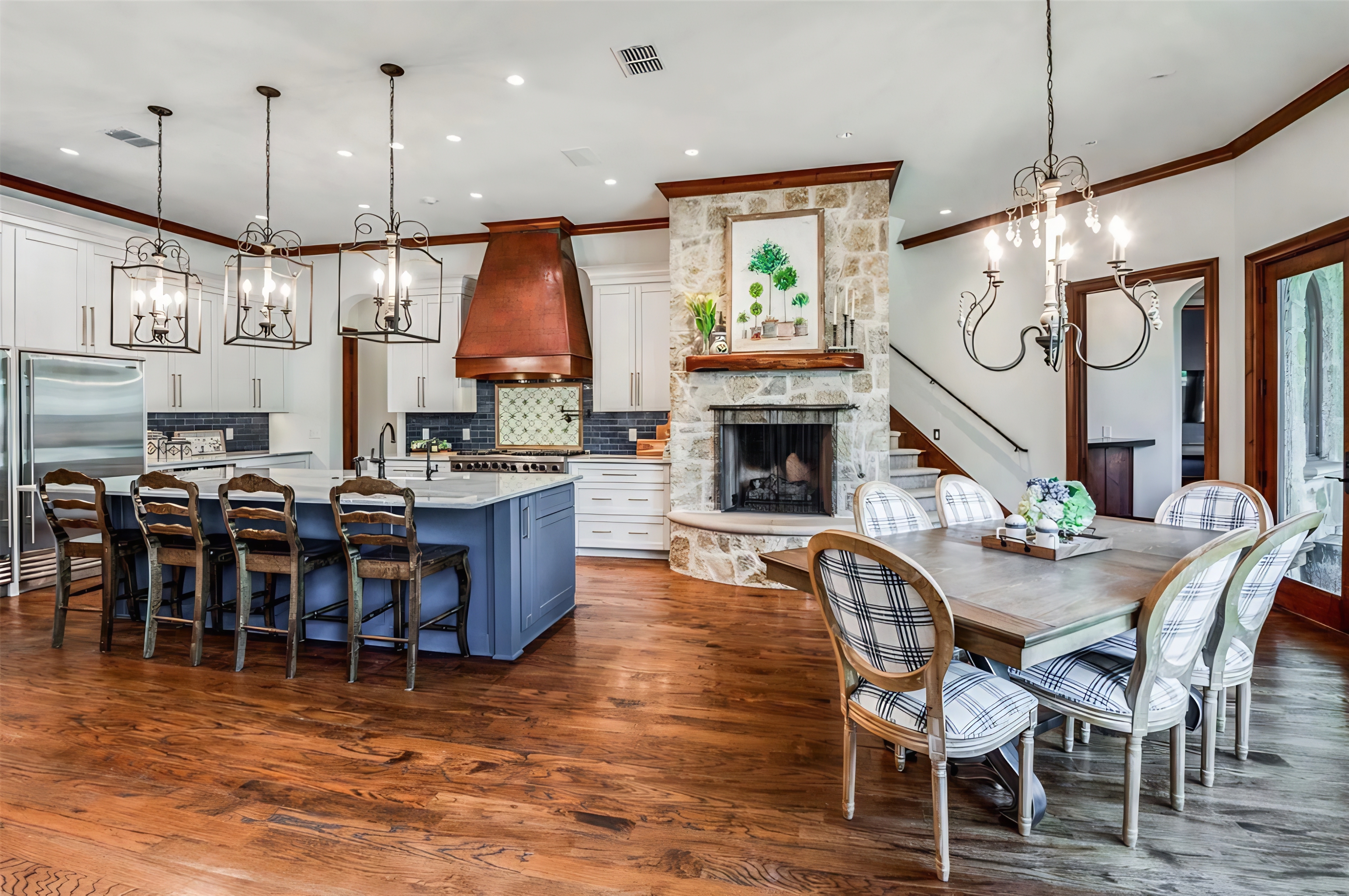 Custom kitchen with blue island, stone fireplace, and designer lighting