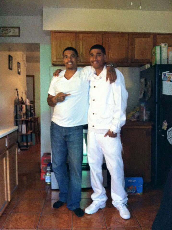 Edwin and Javon standing together, father and son, arms around each other, Javon in an all-white outfit
