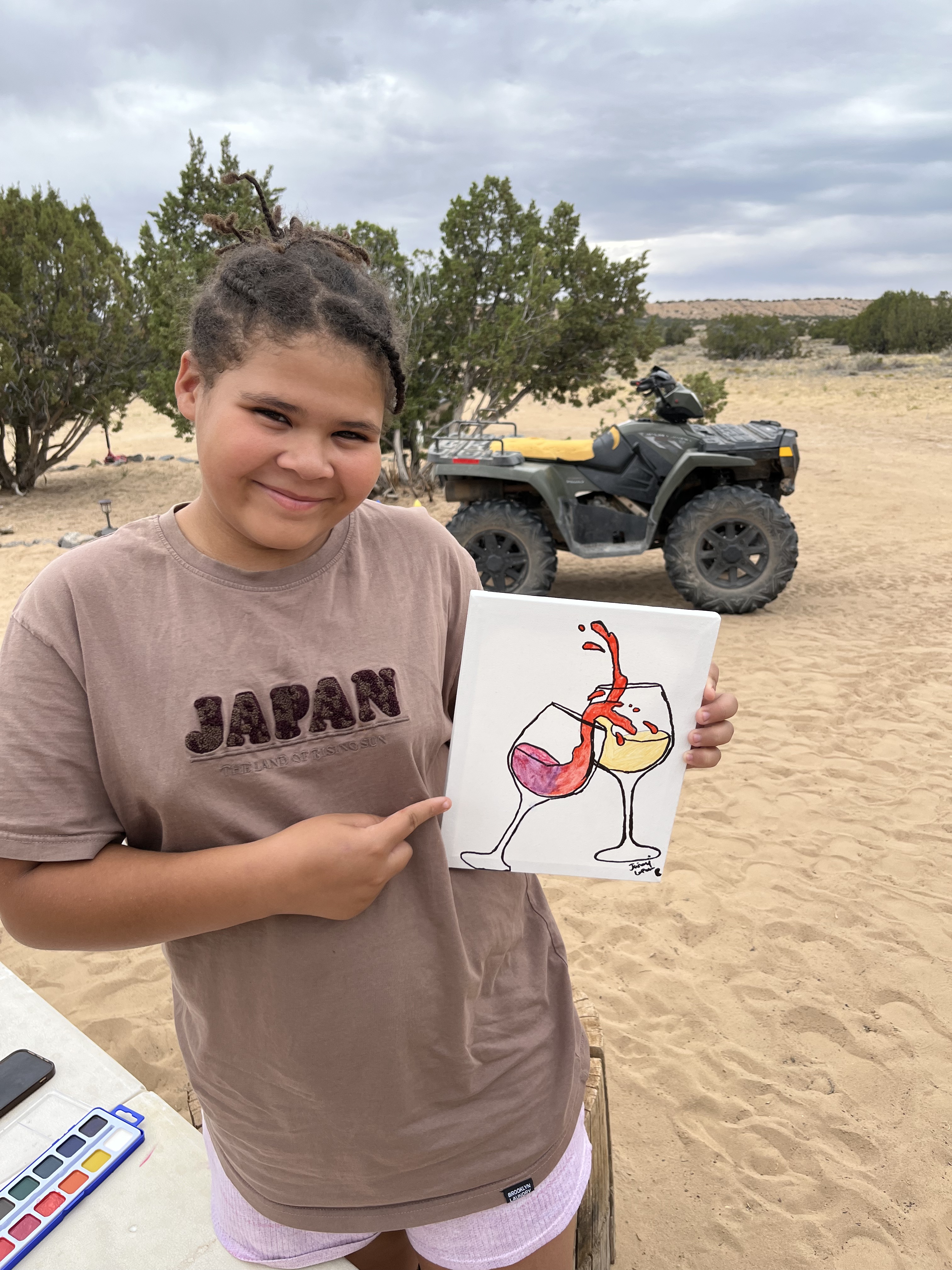 Ja'Nai Lopez proudly holding up her painting outdoors on the farm — creativity, art, and youth learning in action