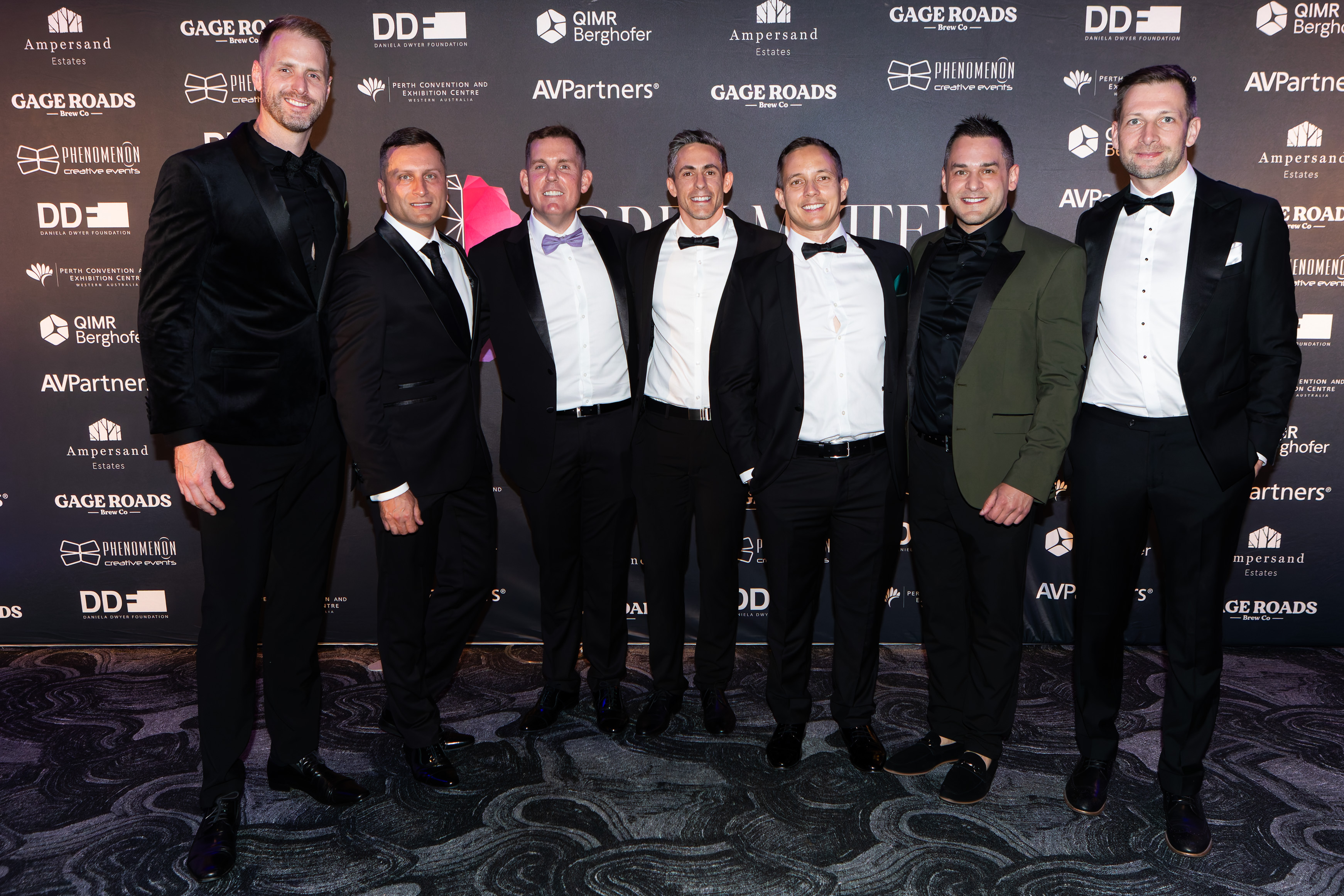 Group of men in black tie at the sponsor wall at the Grey Matter Gala 2025
