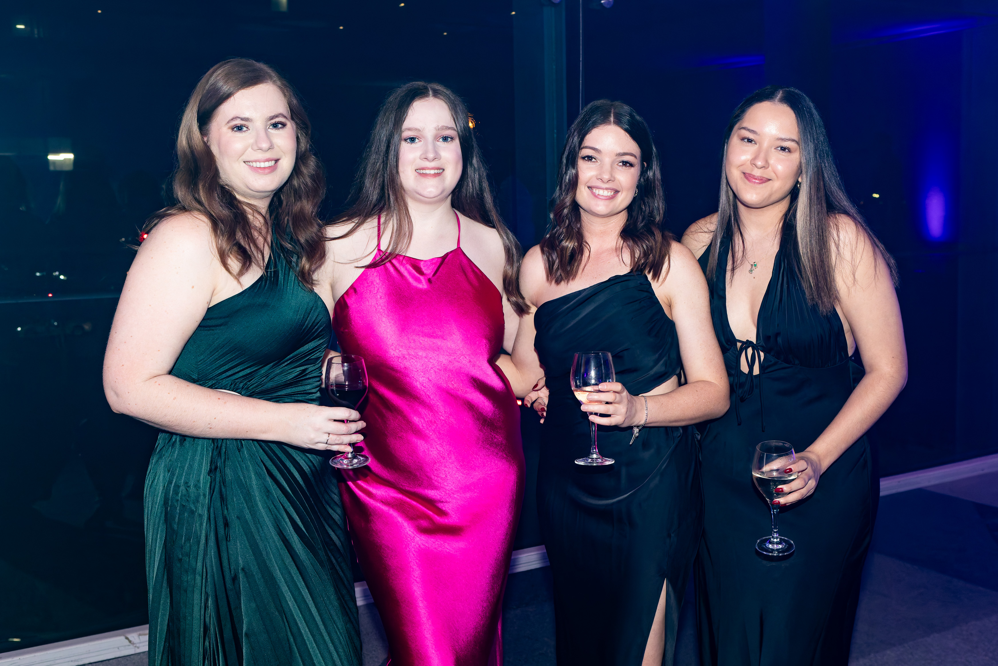 Friends posing together in formal gowns at the Grey Matter Gala 2025