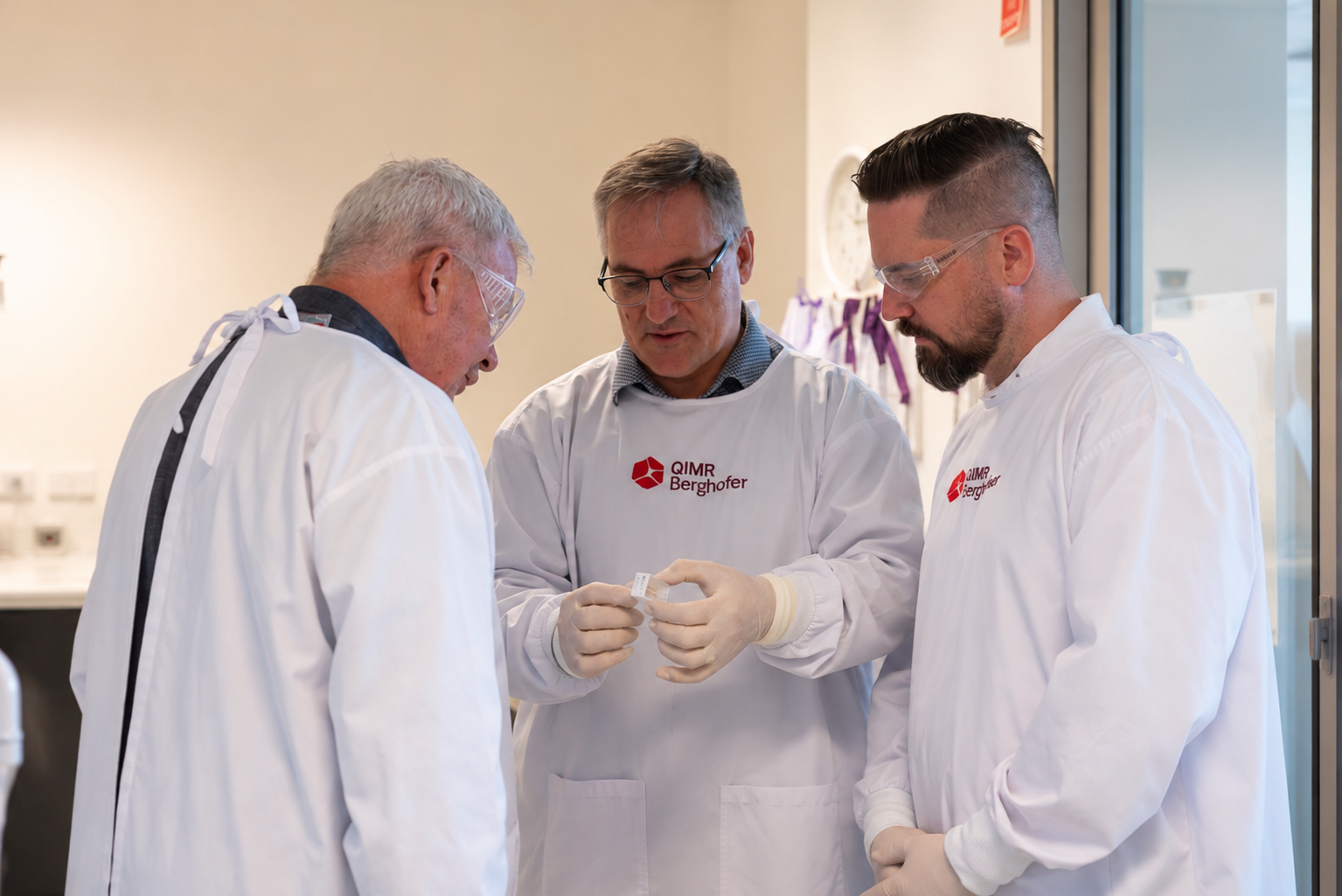 Researchers in lab coats examining samples at QIMR Berghofer