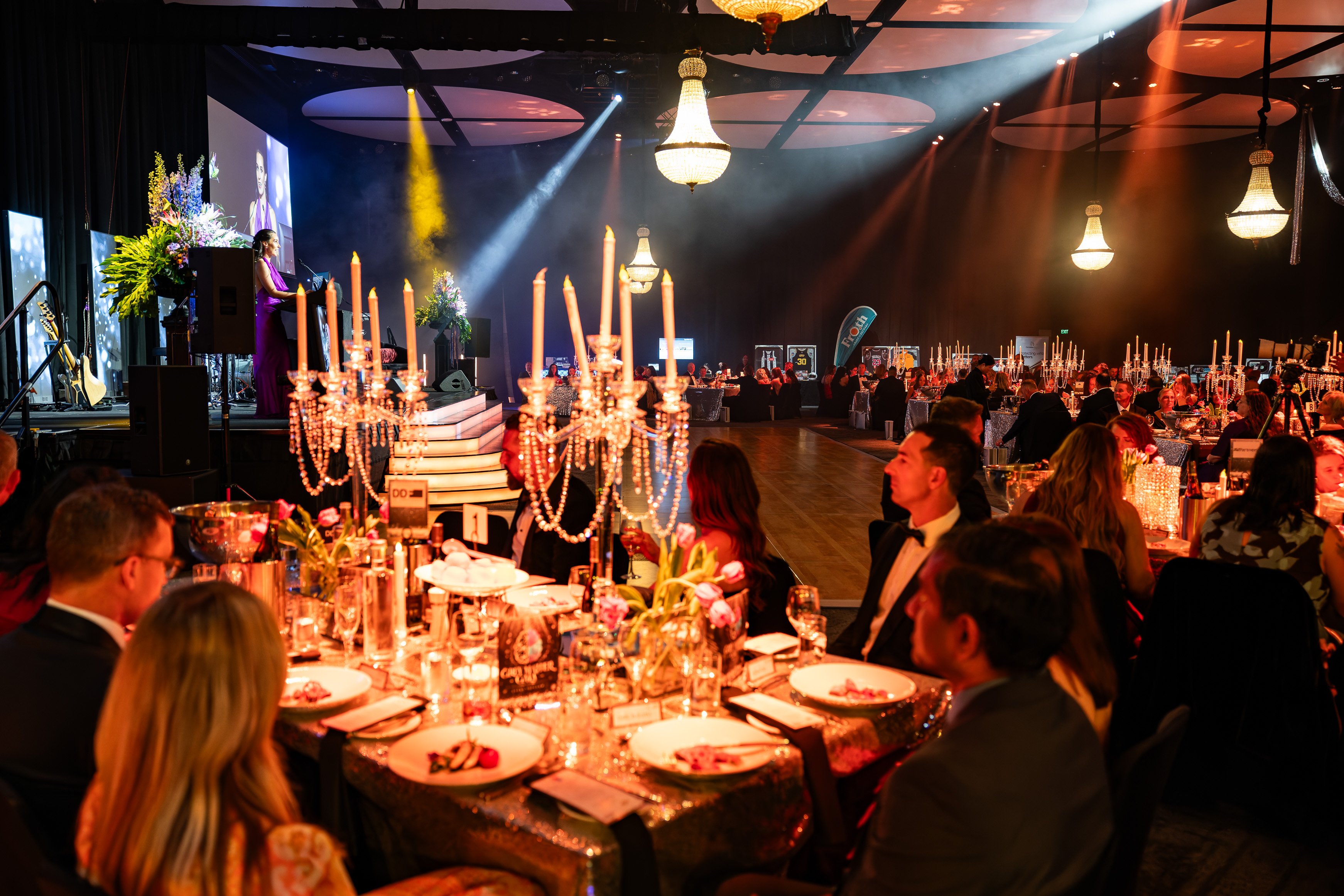 Grey Matter Gala 2026 — guests seated at beautifully decorated tables with crystal candelabras and stage lighting