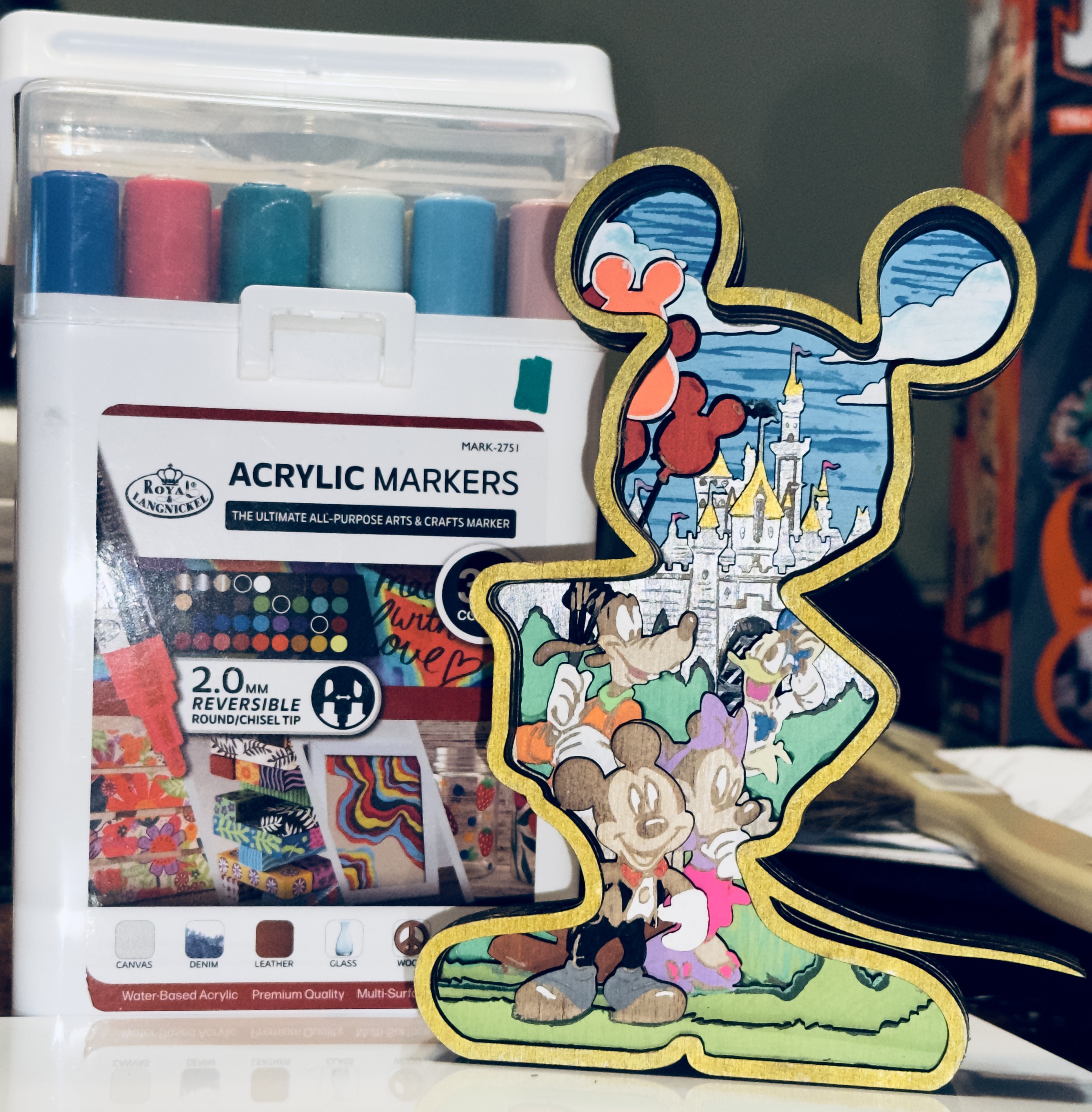 Layered laser-cut wooden character silhouette art with hand-painted castle scene, balloons, and colorful details