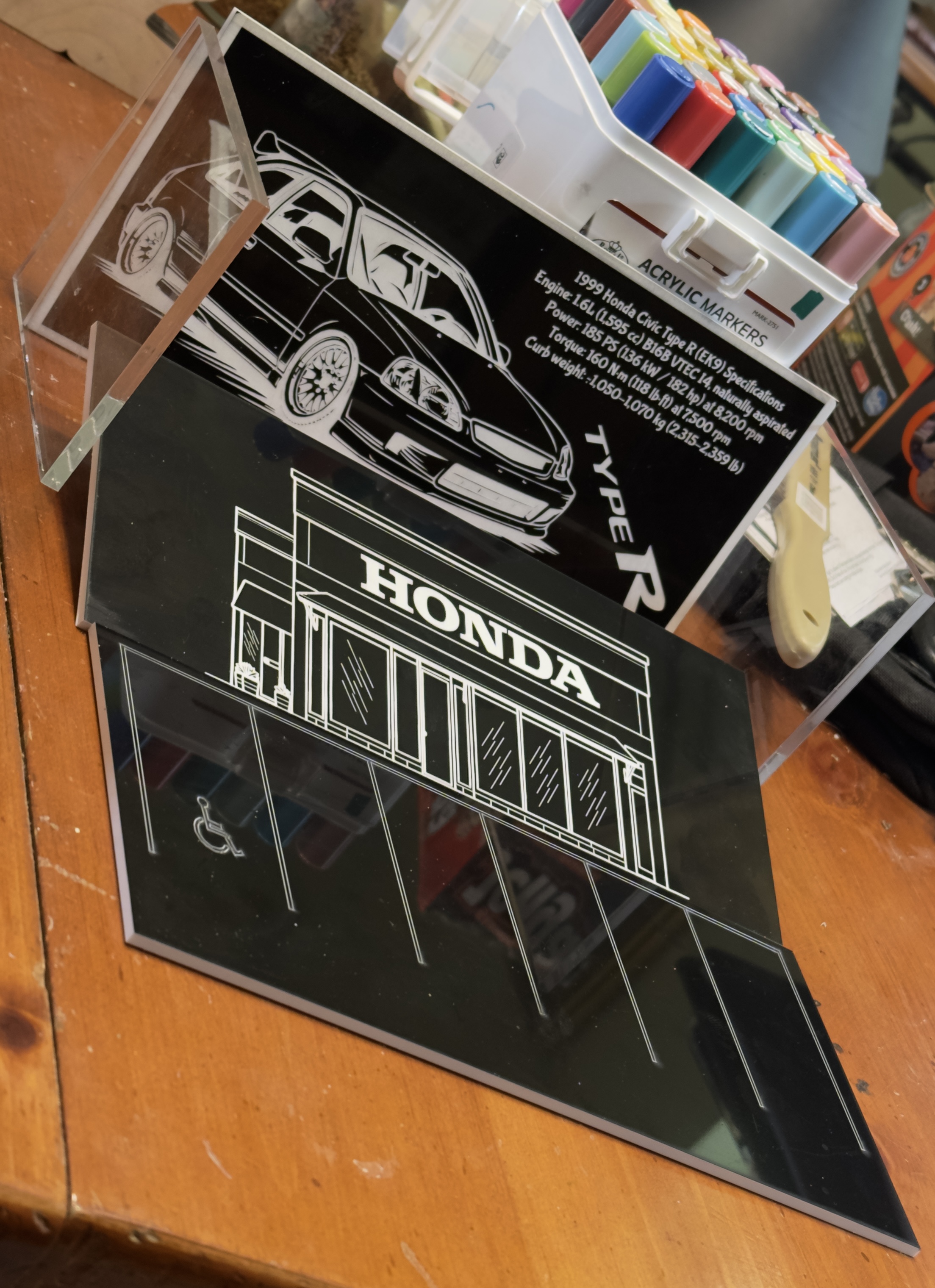 Laser-engraved acrylic automotive art featuring a 1999 Honda Civic Type R with specs and a Honda dealership storefront design