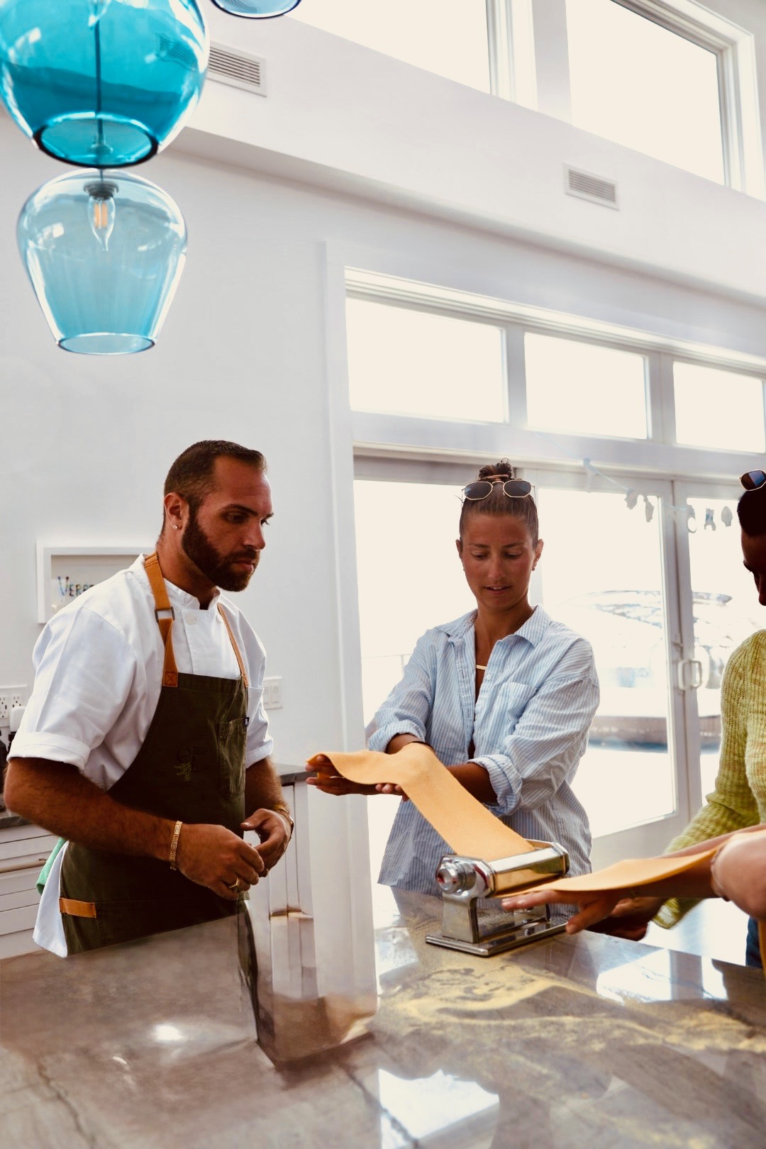 Chef Francesco La Russa guiding a guest through rolling fresh pasta dough at a cooking class