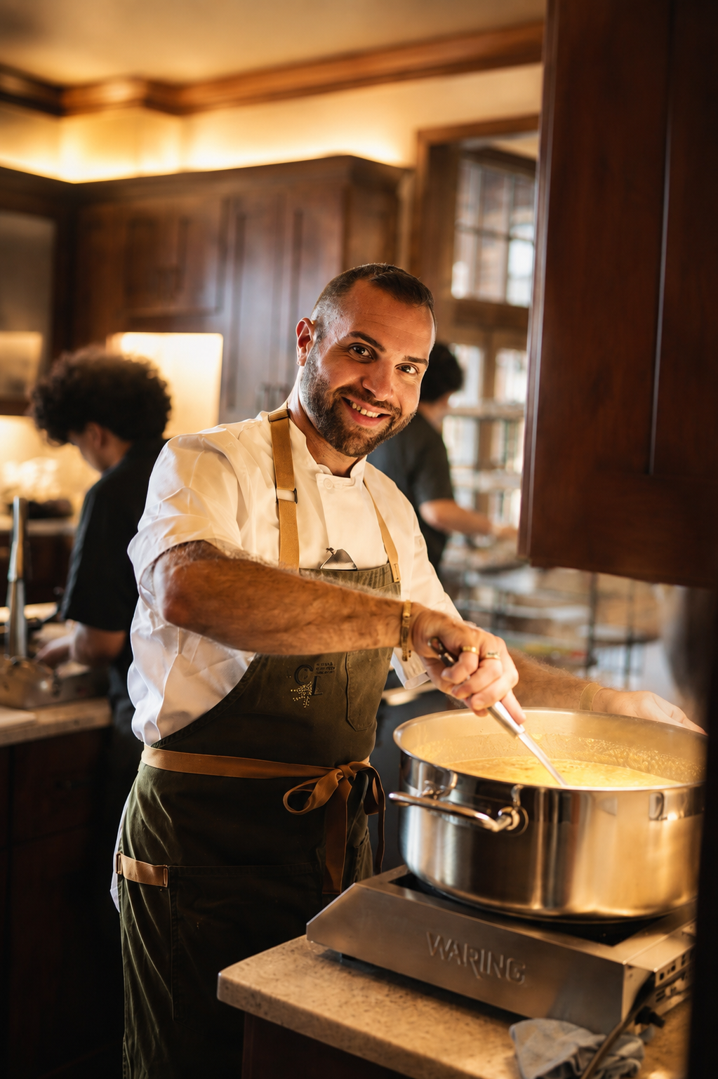 Private chef Francesco La Russa smiling while cooking at a luxury catering event in the Hamptons
