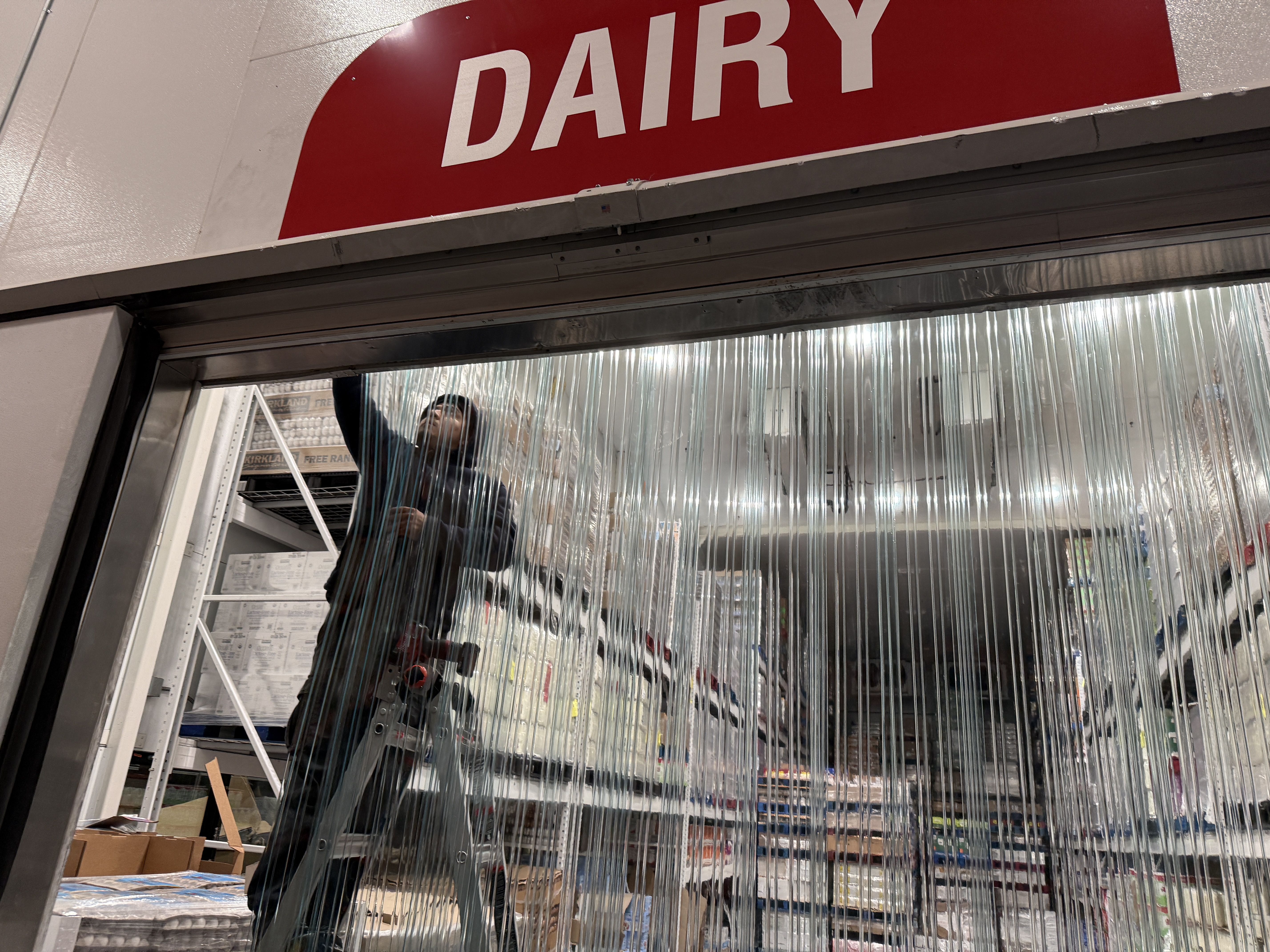 Cal Gaskets technician installing PVC strip curtains at a grocery store dairy section
