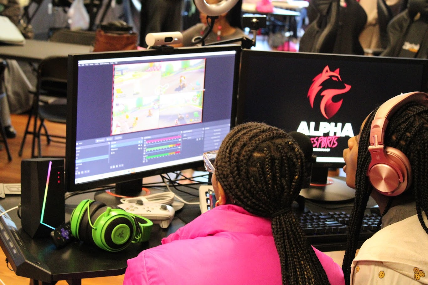 Girl gaming at a PC station with Alpha Esports branding during a Girls Game Too event