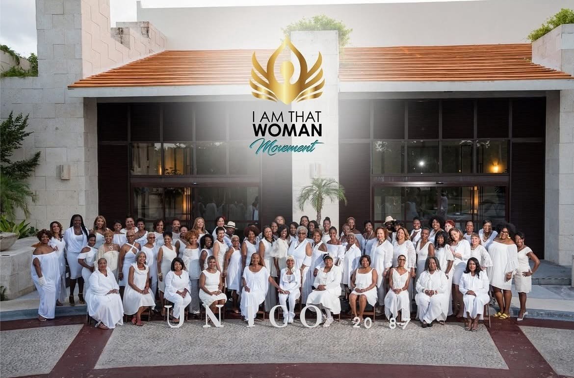 Large group photo in white outfits in front of the IATW Movement banner