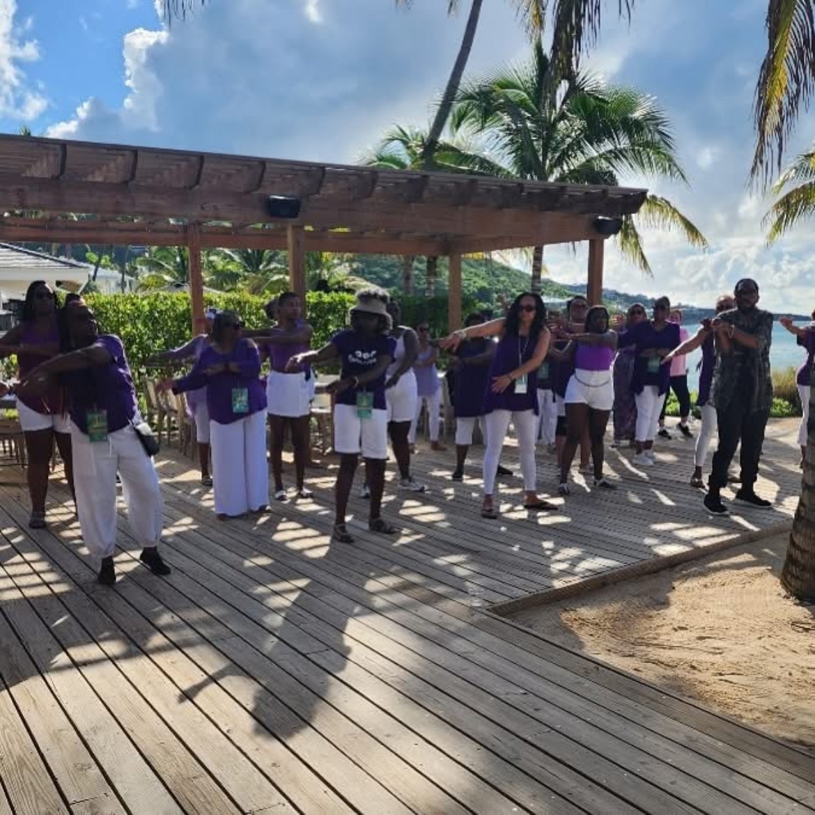 Women in purple and white dancing on a beachside boardwalk