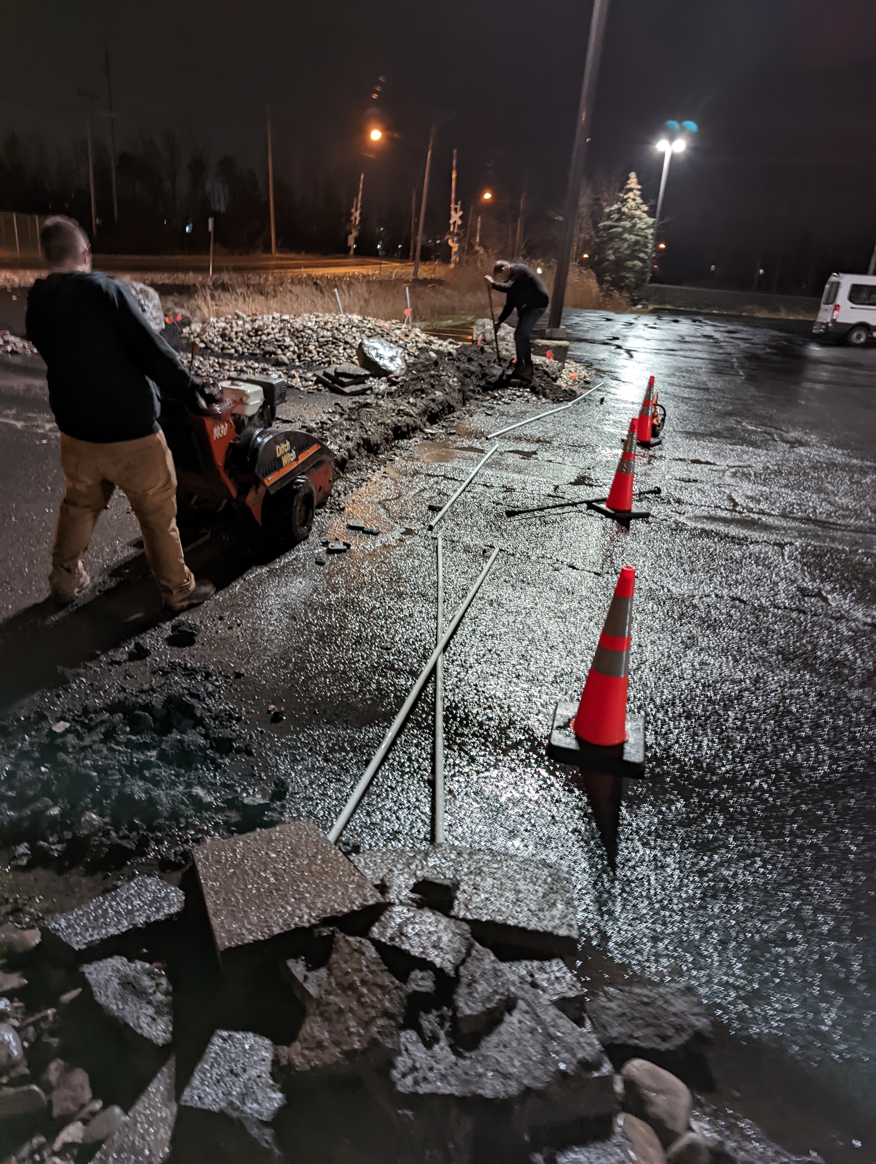 Nighttime underground electrical conduit installation in commercial parking lot by Premier Alarms and Electric โ Monroe County NY