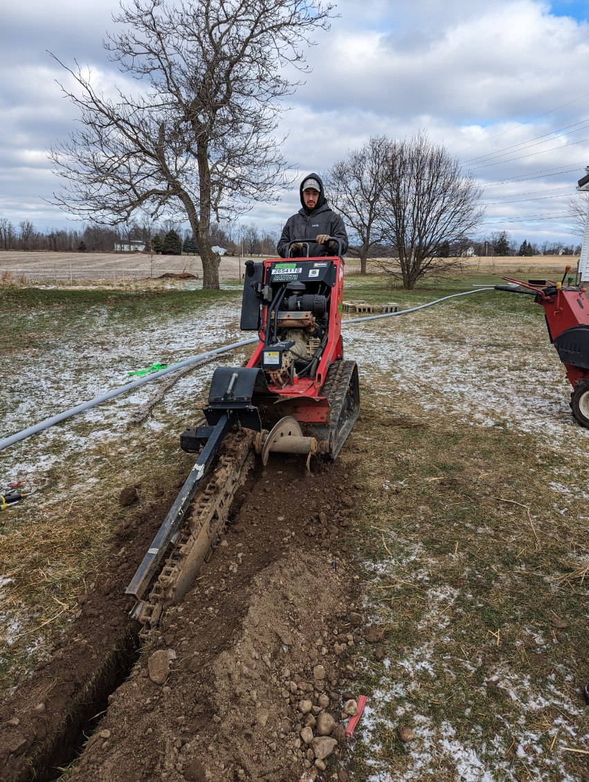 Premier Electric crew operating Toro trencher for underground electrical work Rochester NY