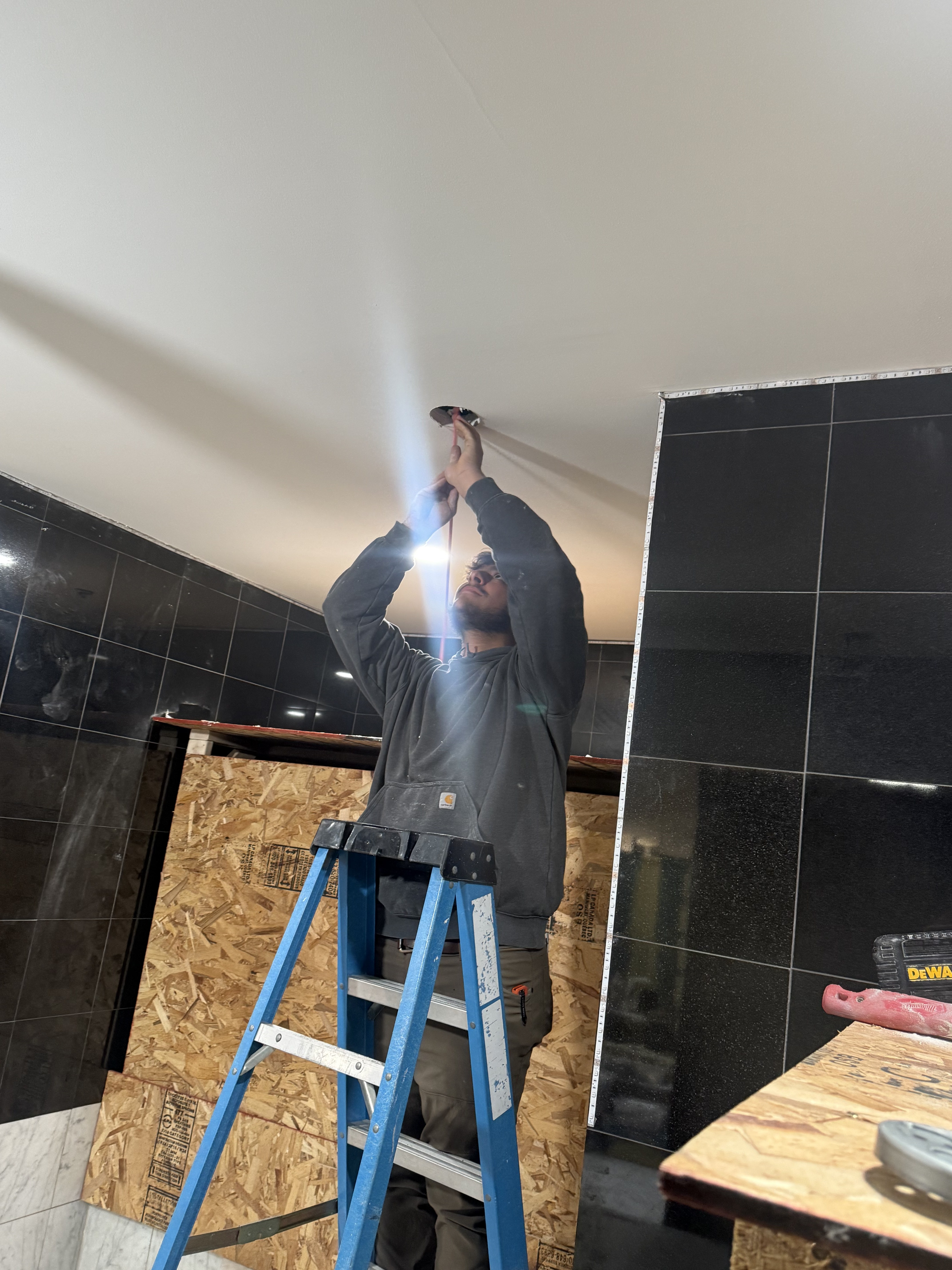 Premier Alarms and Electric technician installing recessed lighting in commercial space under construction โ Monroe County NY