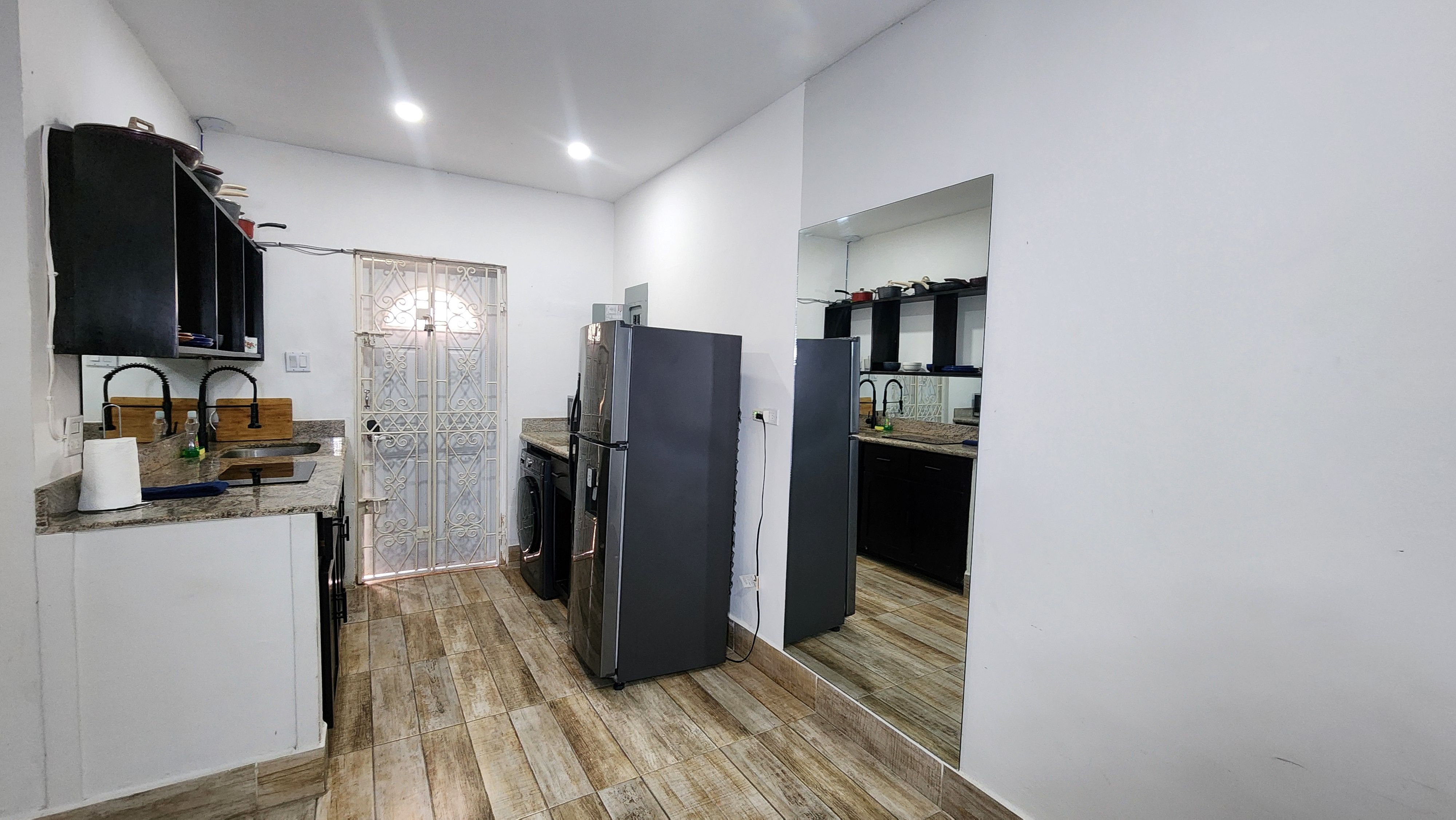 MG7 kitchen — black cabinets, stainless fridge, washer, granite counter, full-length mirror