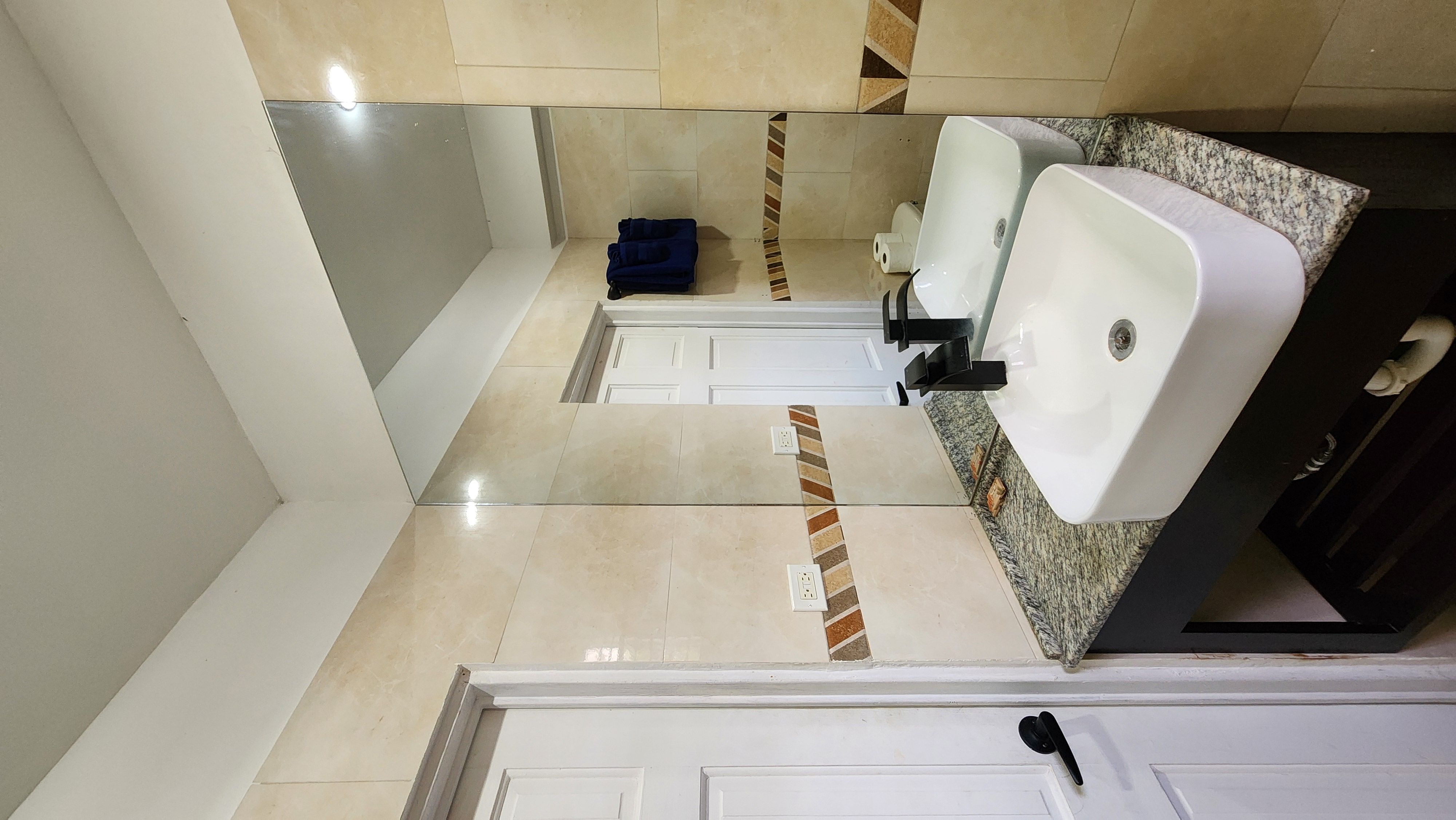 MG17 bathroom — vessel sink, black matte faucet, granite counter, tiled walls, blue towels