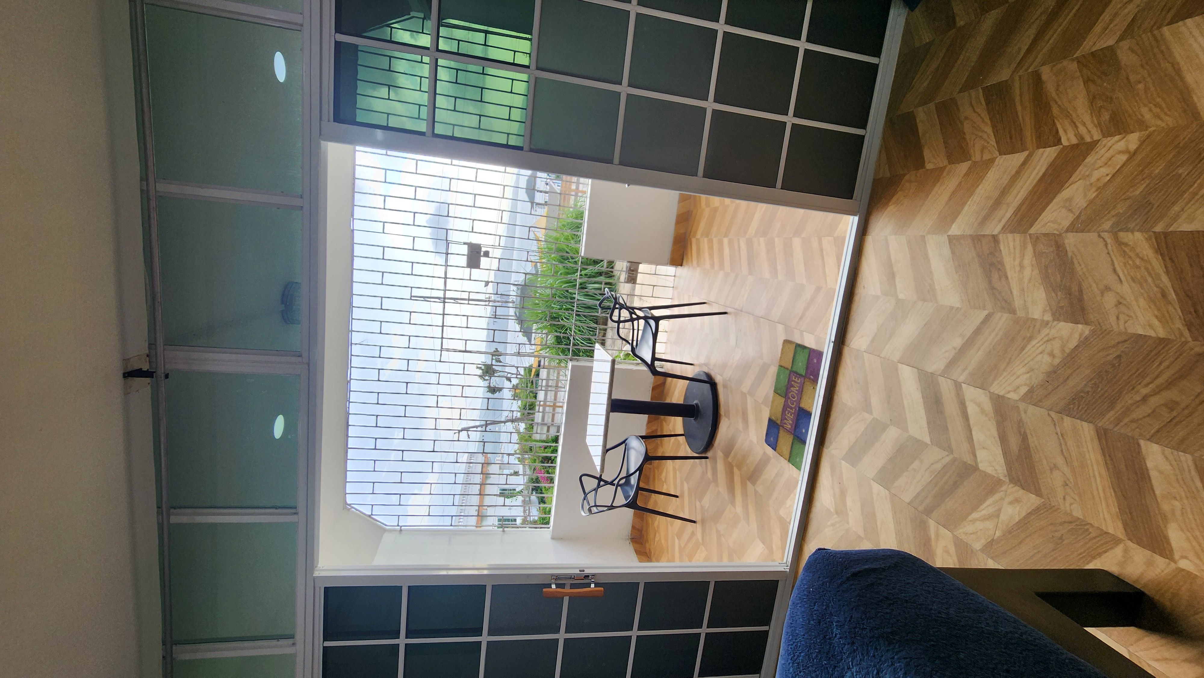 MG6 view from inside to open balcony door — garden, ocean glimpse, herringbone floor