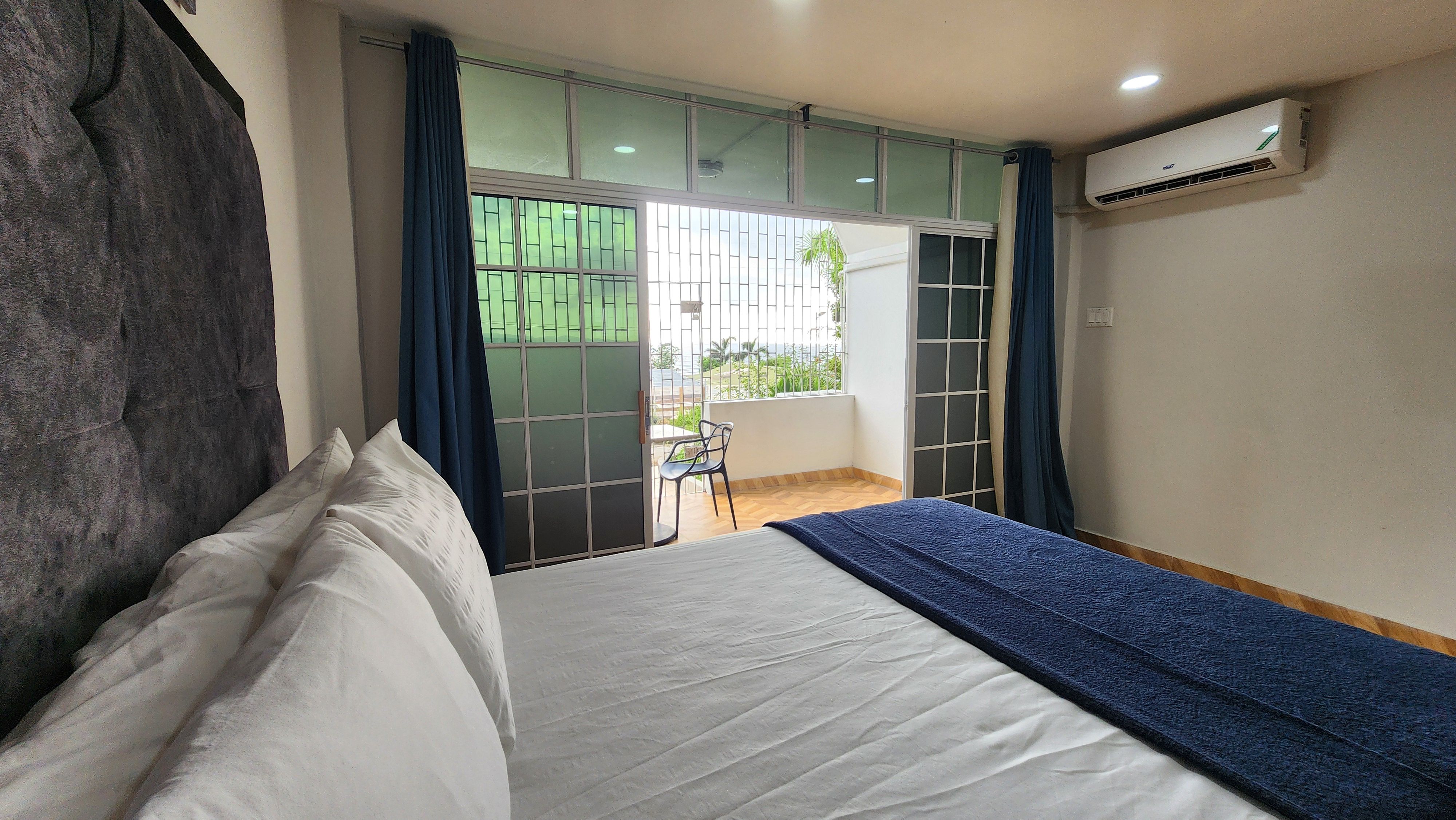 MG6 queen bed with view straight to open balcony door — palm trees and ocean beyond