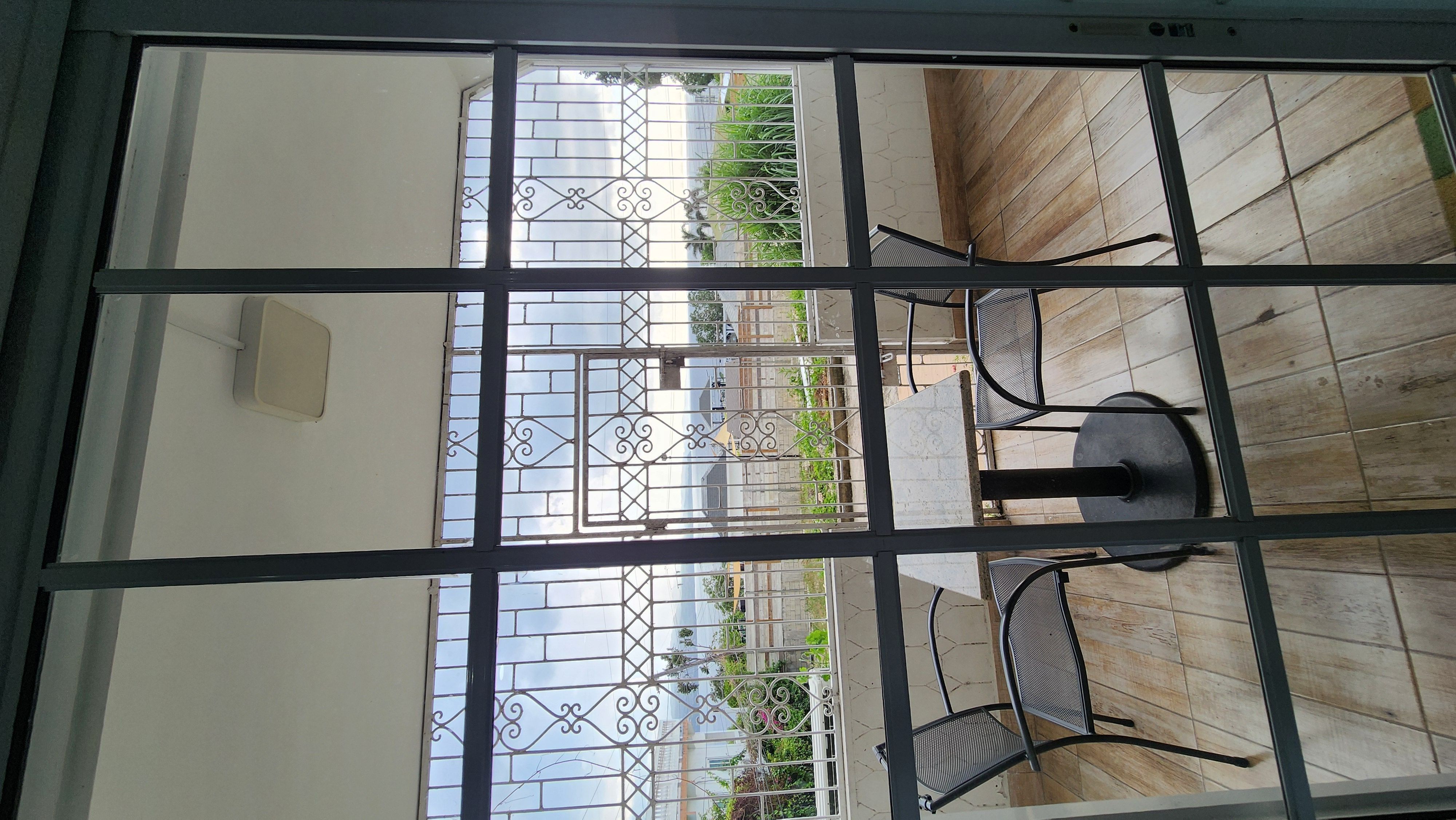 MG7 private balcony — ornate iron gate, outdoor seating, sky and tropical greenery