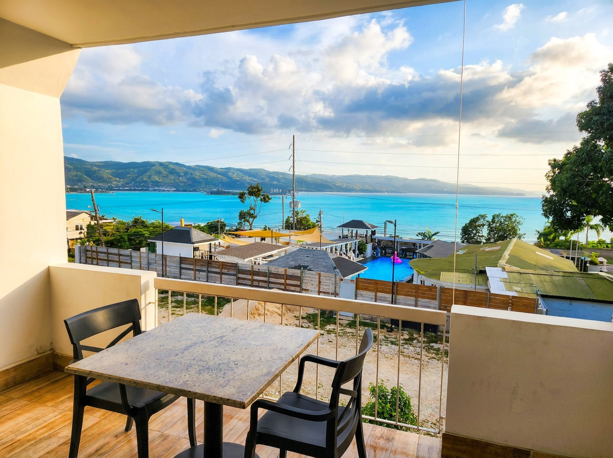 MG10 private balcony — outdoor dining table and chairs, pool, ocean and mountain views beyond