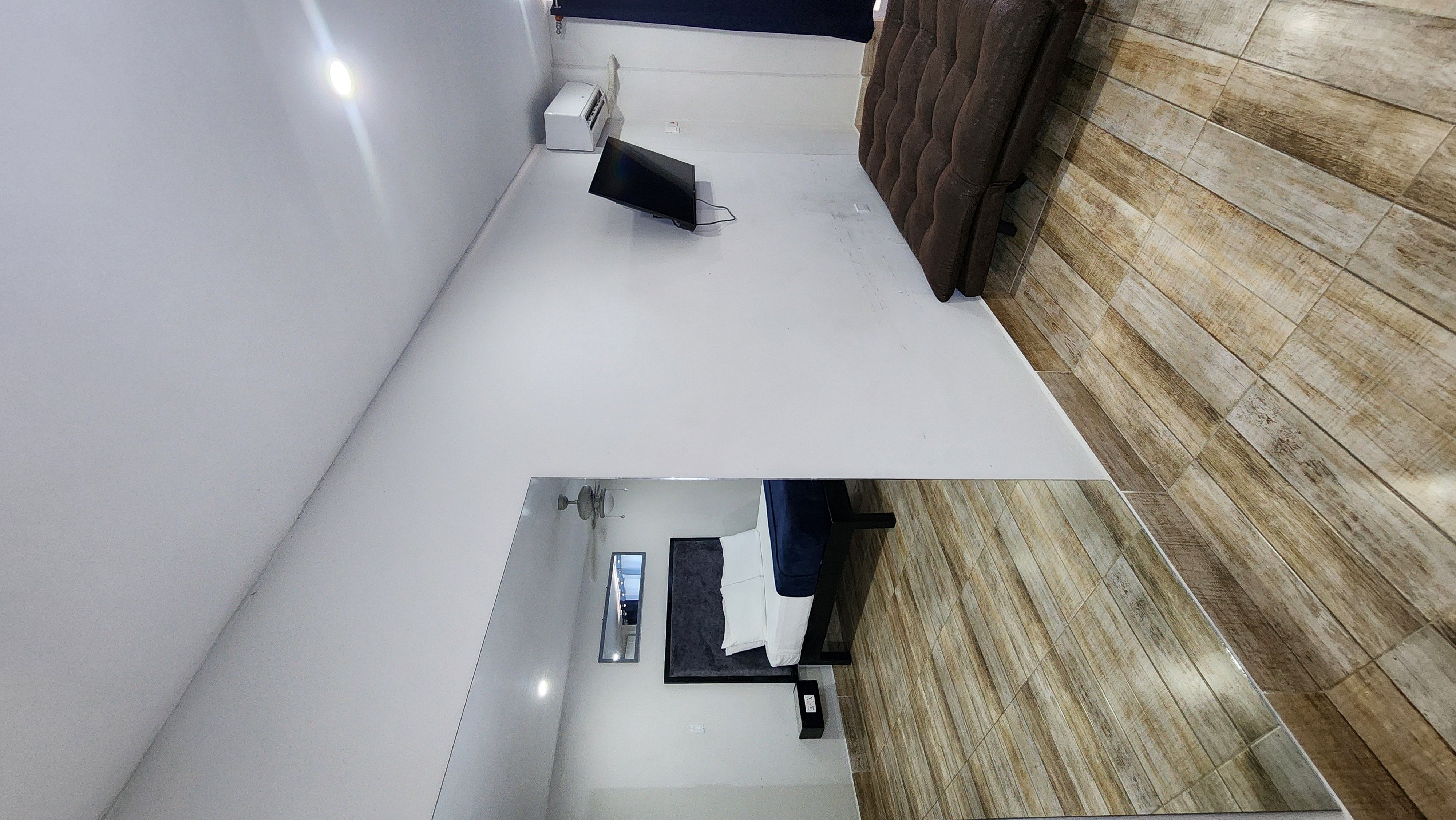 MG7 room with mirror reflection — tufted headboard, wall-mounted TV and AC