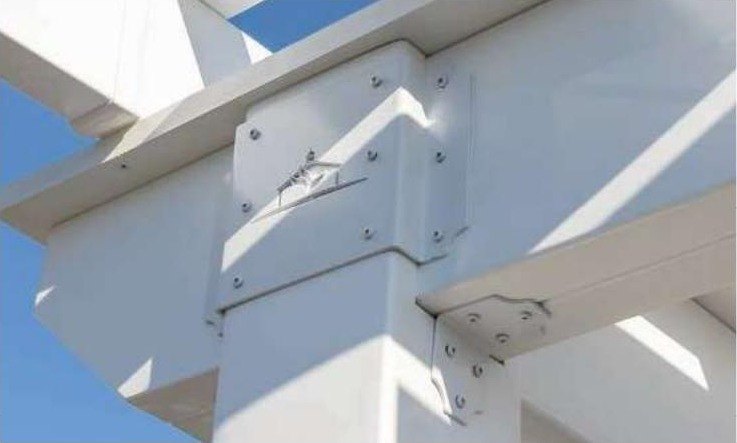 Close-up of a custom laser-cut powder-coated steel bracket joining a post and header on a white vinyl Hollander pergola