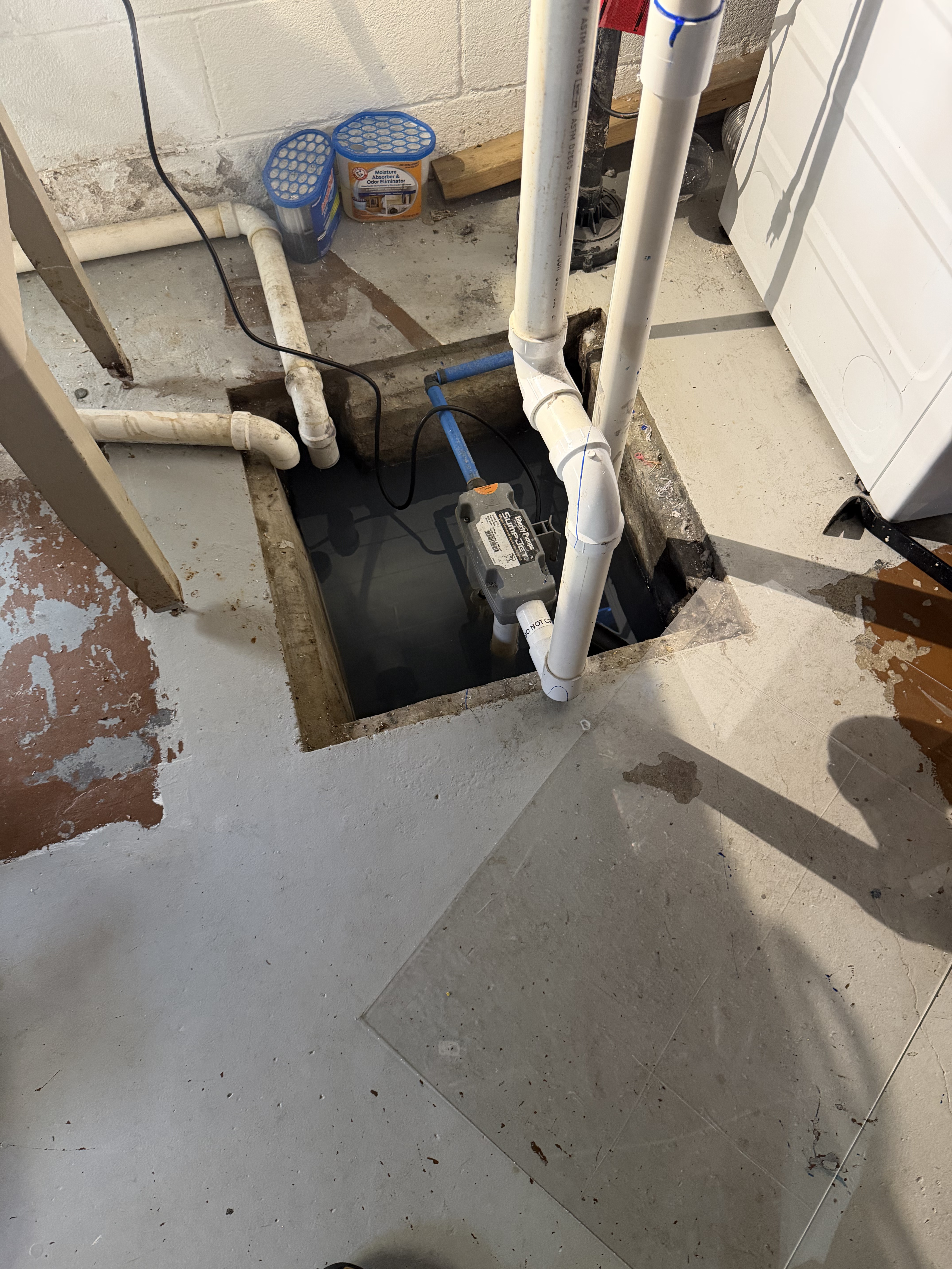 Before: Open sump pit with standing water and exposed pump