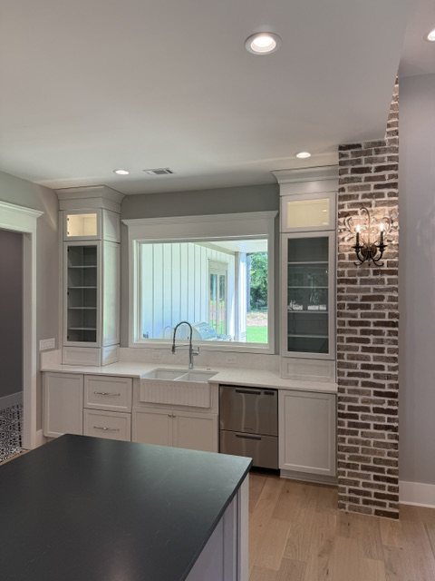 Kitchen with farmhouse sink, glass-front cabinets and exposed brick accent