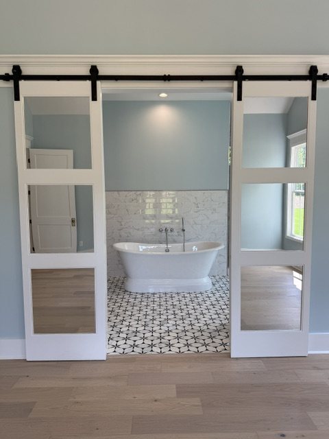 Master bath with barn doors, freestanding tub and patterned tile floor