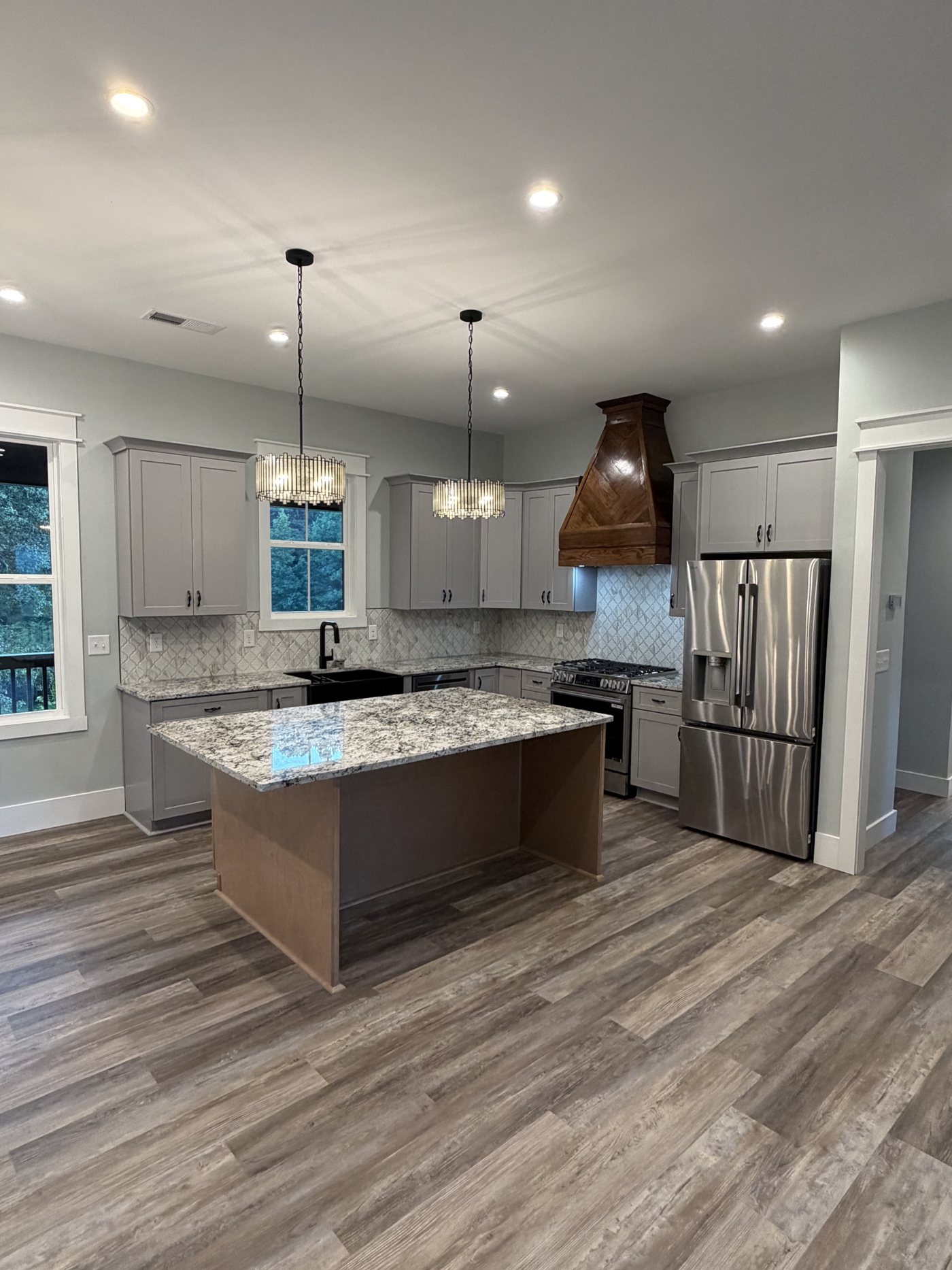 Kitchen with granite island, custom wood range hood and pendant lighting