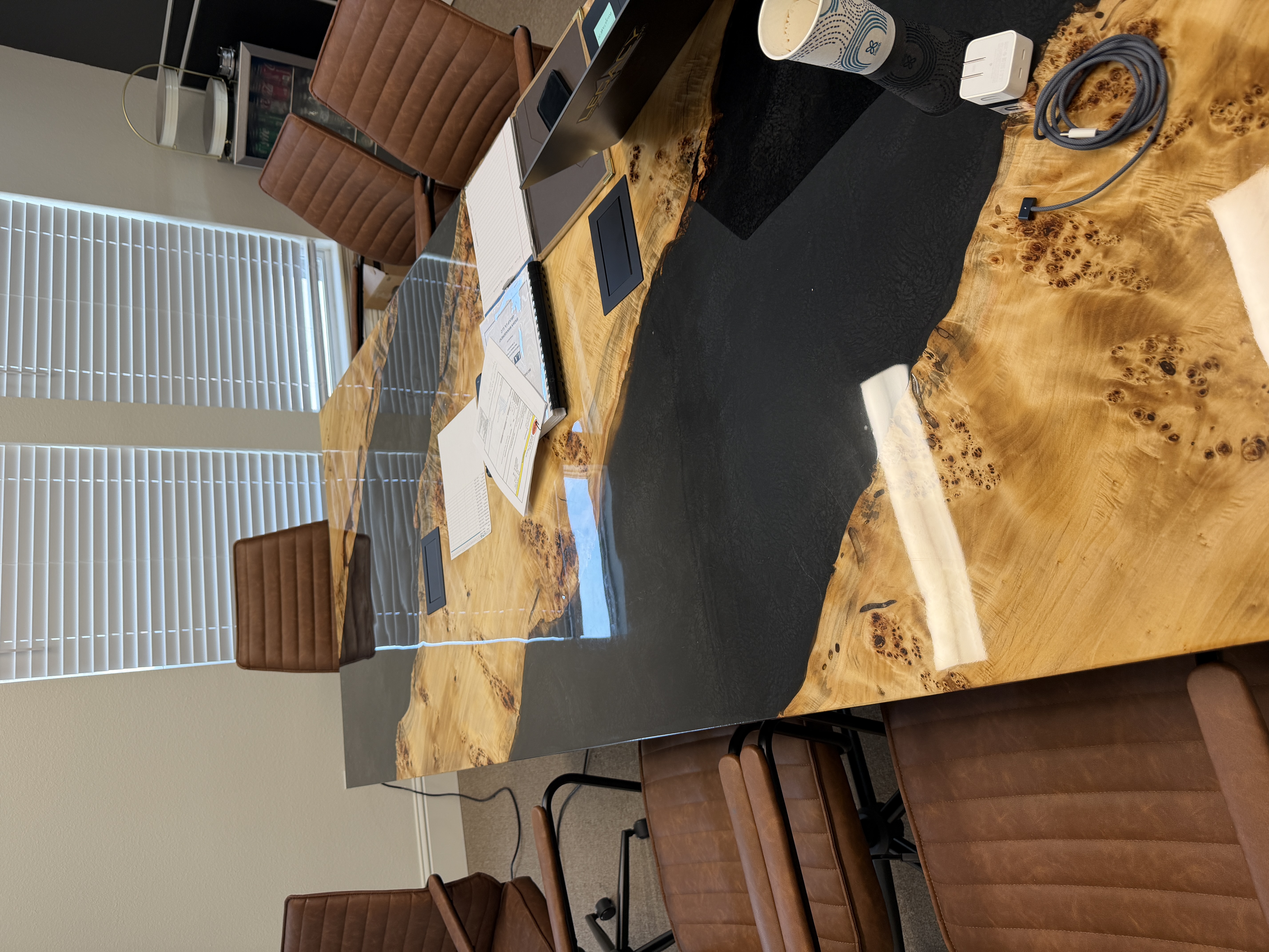 Burl wood conference table with black epoxy river and leather chairs in Louisiana office