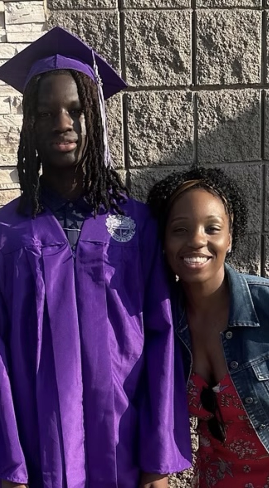 Youth graduate in purple cap and gown with mentor