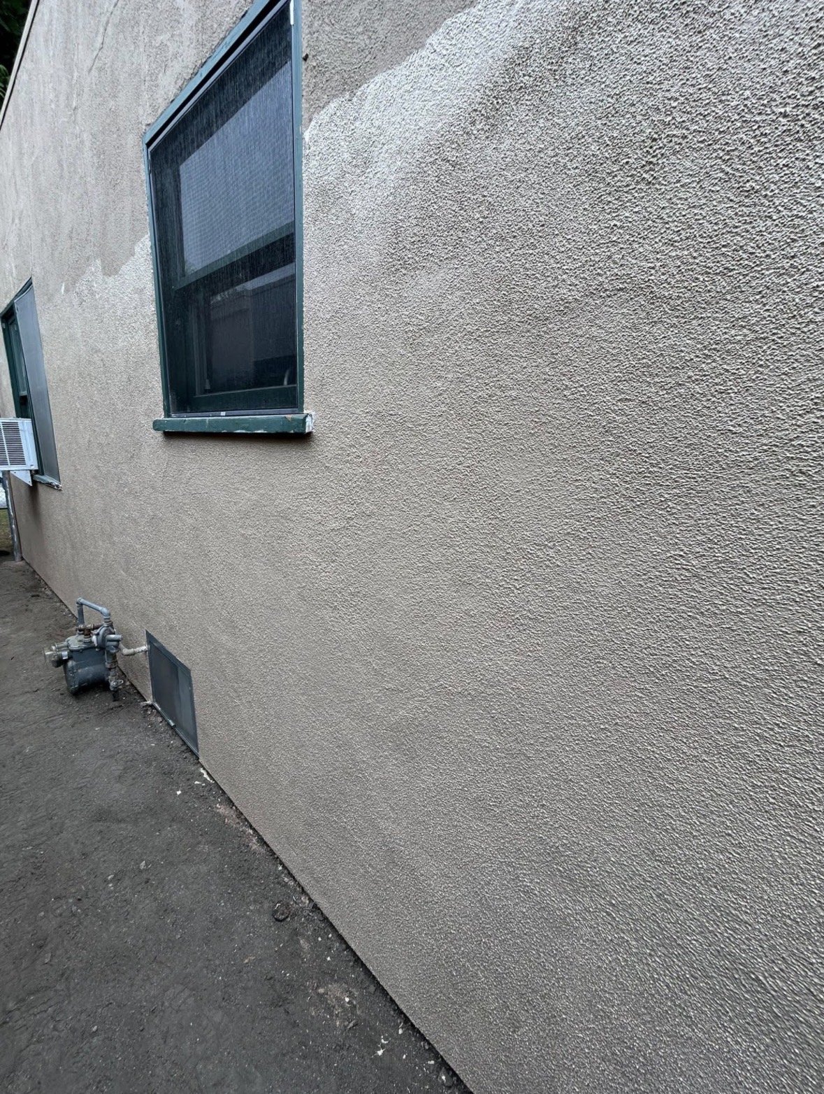 Completed stucco exterior wall with window and gas meter — textured finish by PMR Projects