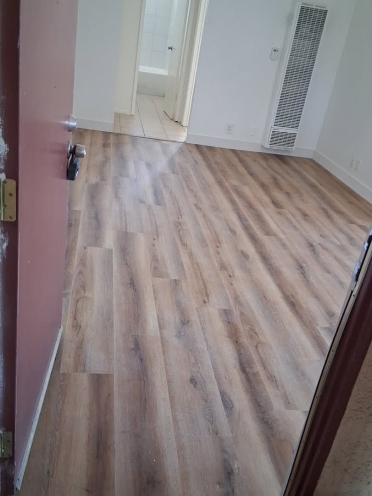 LVP flooring installed at unit entry — clean finish with new baseboards by PMR Projects